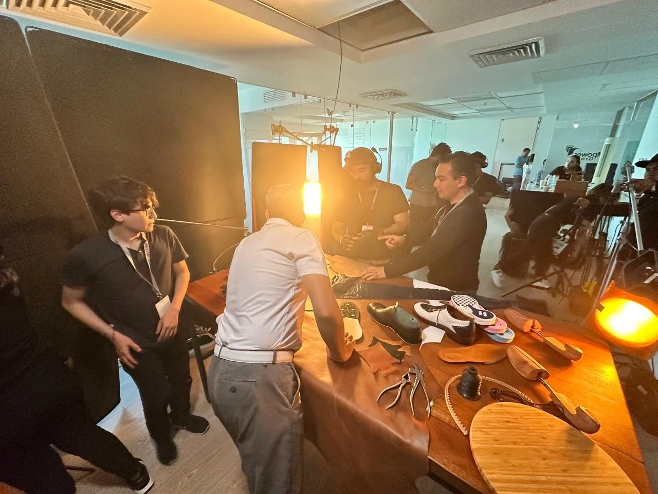 People filming a scene in a studio, with various equipment and props on a wooden table.