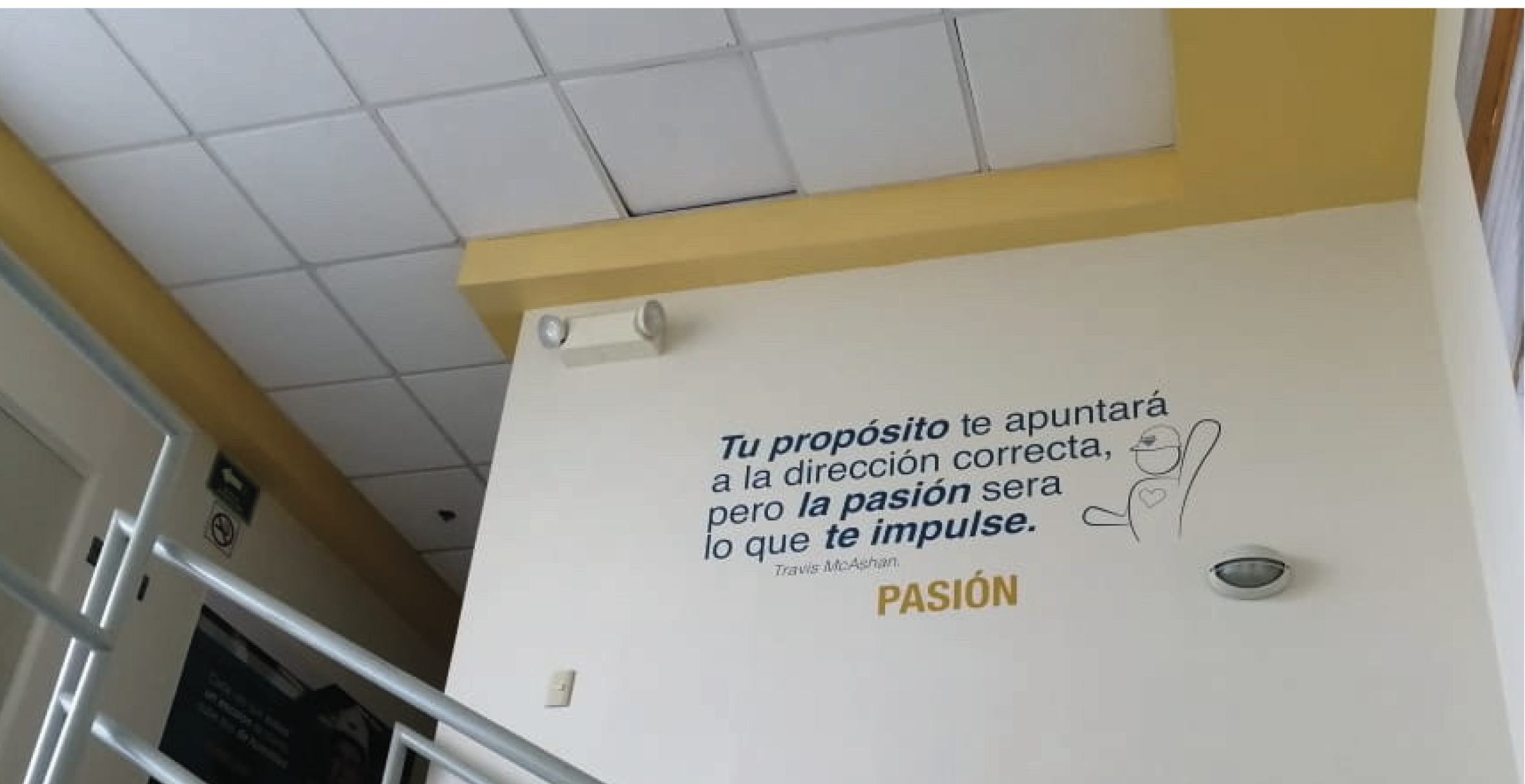 A wall with a motivational quote in Spanish and a simple drawing of a smiling person with a heart on their chest. The quote reads: "Tu propósito te apuntará a la dirección correcta, pero la pasión será lo que te impulse." The word "PASIÓN" is highlig
