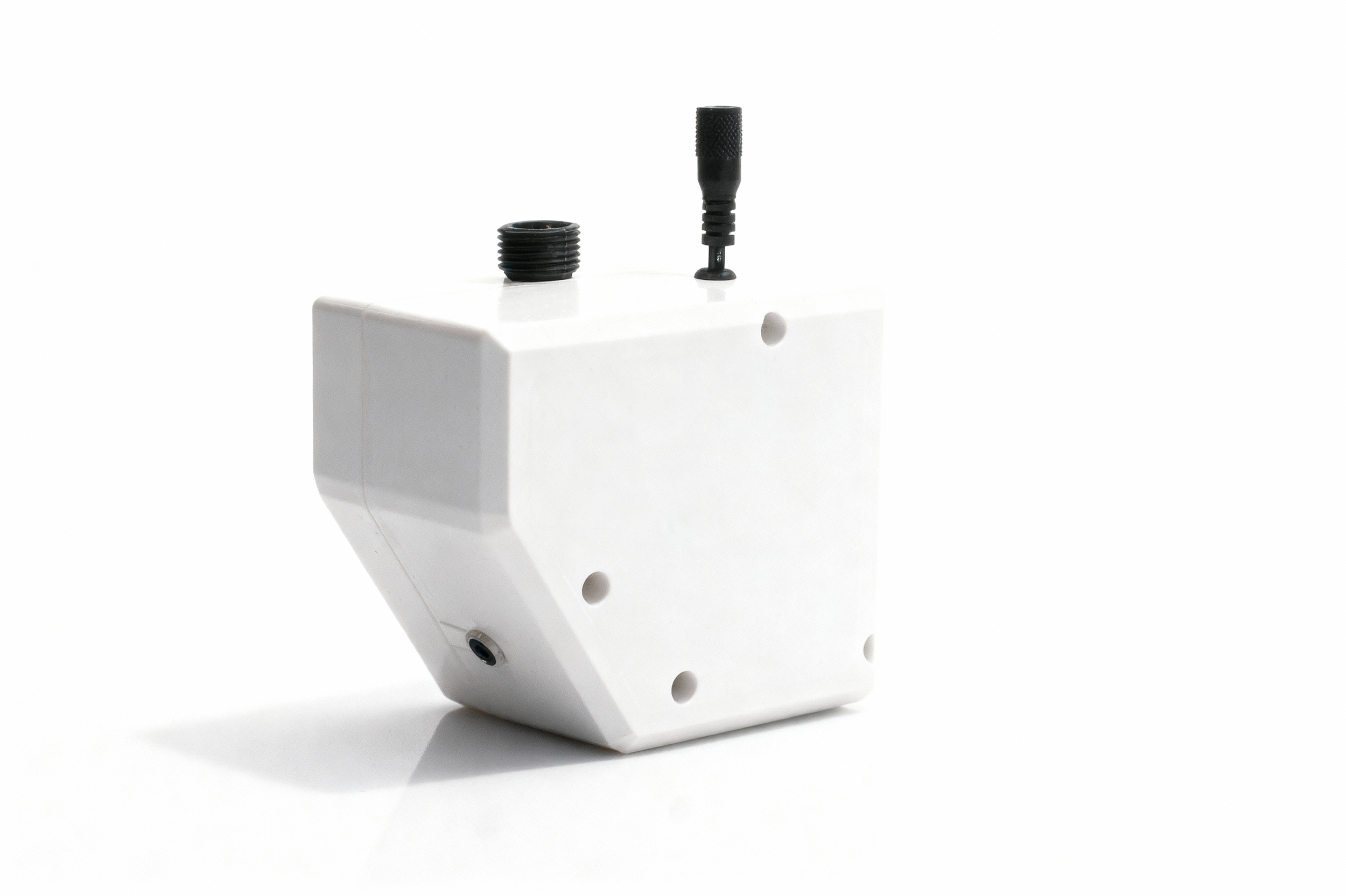 A white rectangular electronic device with a black antenna and two black screw-like components on top, placed on a white surface with a plain white background.