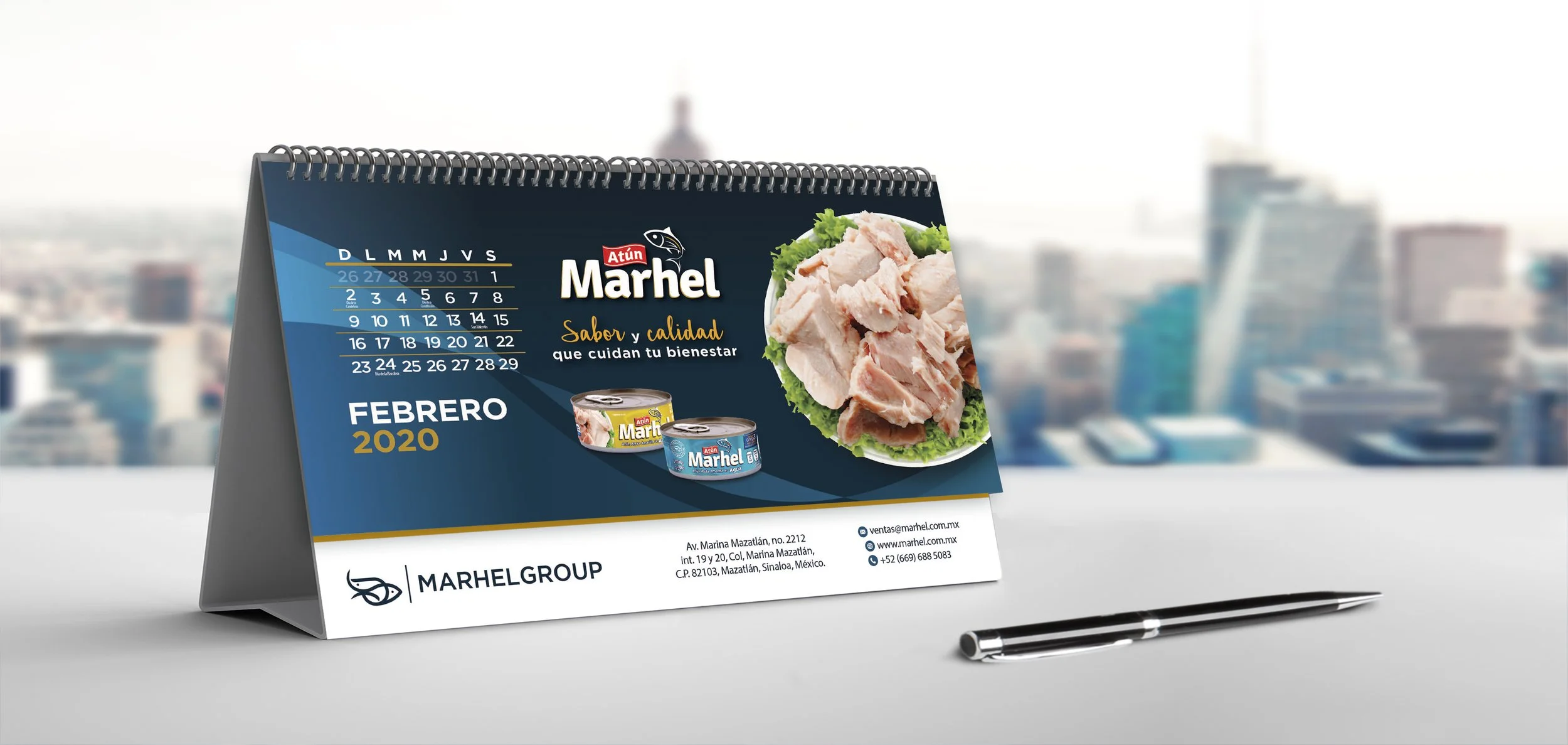 Desk calendar featuring an advertisement for Marhel canned tuna, with a city skyline in the background, and a pen placed next to it.