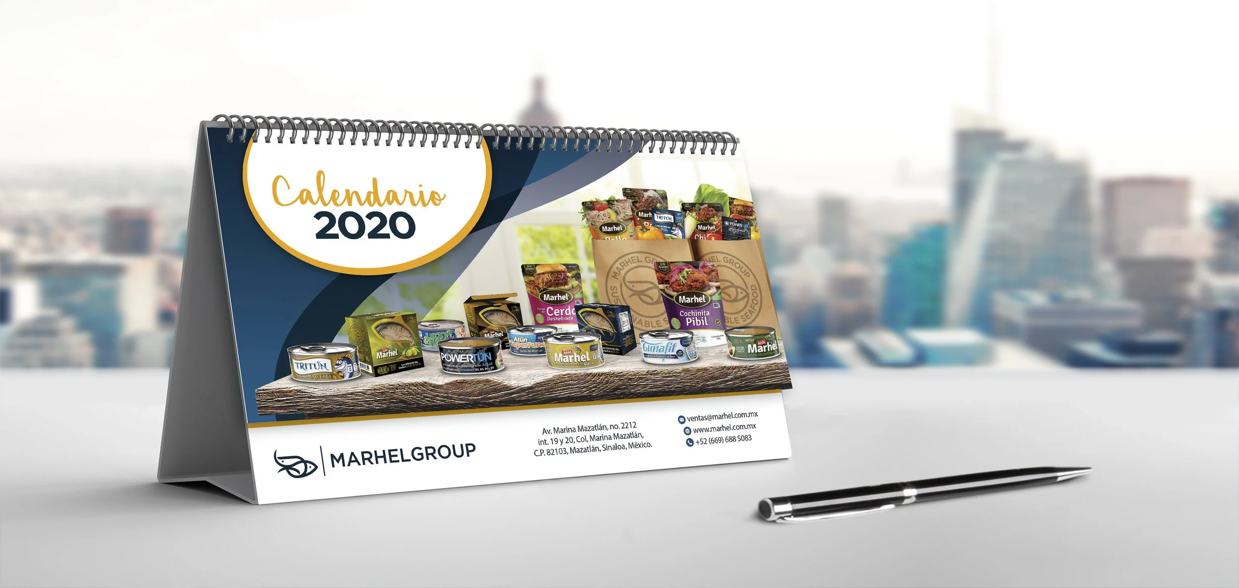 Desk calendar for 2020 displaying canned seafood products from Marhel Group, with contact information and a pen on the table.