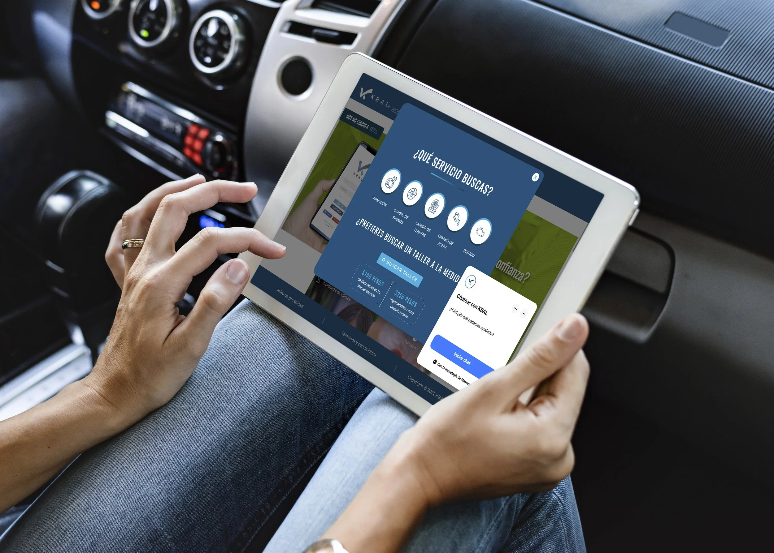 Person holding a tablet inside a car, showing a website for vehicle services with options like oil change and tire change.
