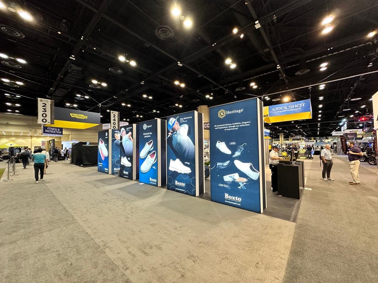 Exhibition hall with booths displaying shoes and sneaker brands, with visitors walking around.