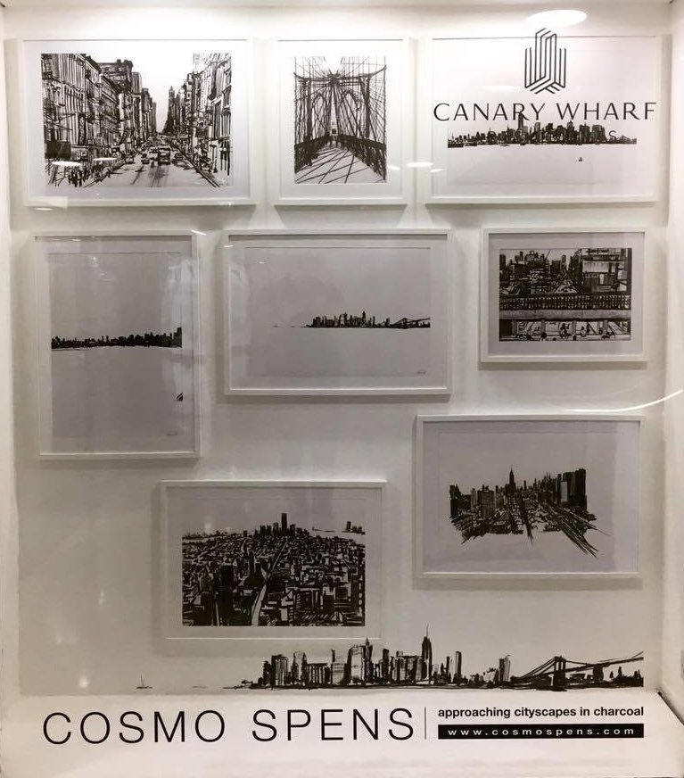 A display of nine black and white sketches of cityscapes, bridges, and urban scenes on a white wall, with text at the bottom reading 'COSMO SPENS' and a website URL.