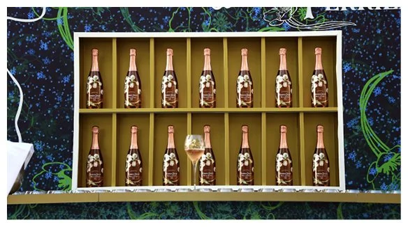 Une display avec plusieurs bouteilles de champagne dans une vitrine avec une seule bouteille ouverte et un verre de champagne rempli en dessous.