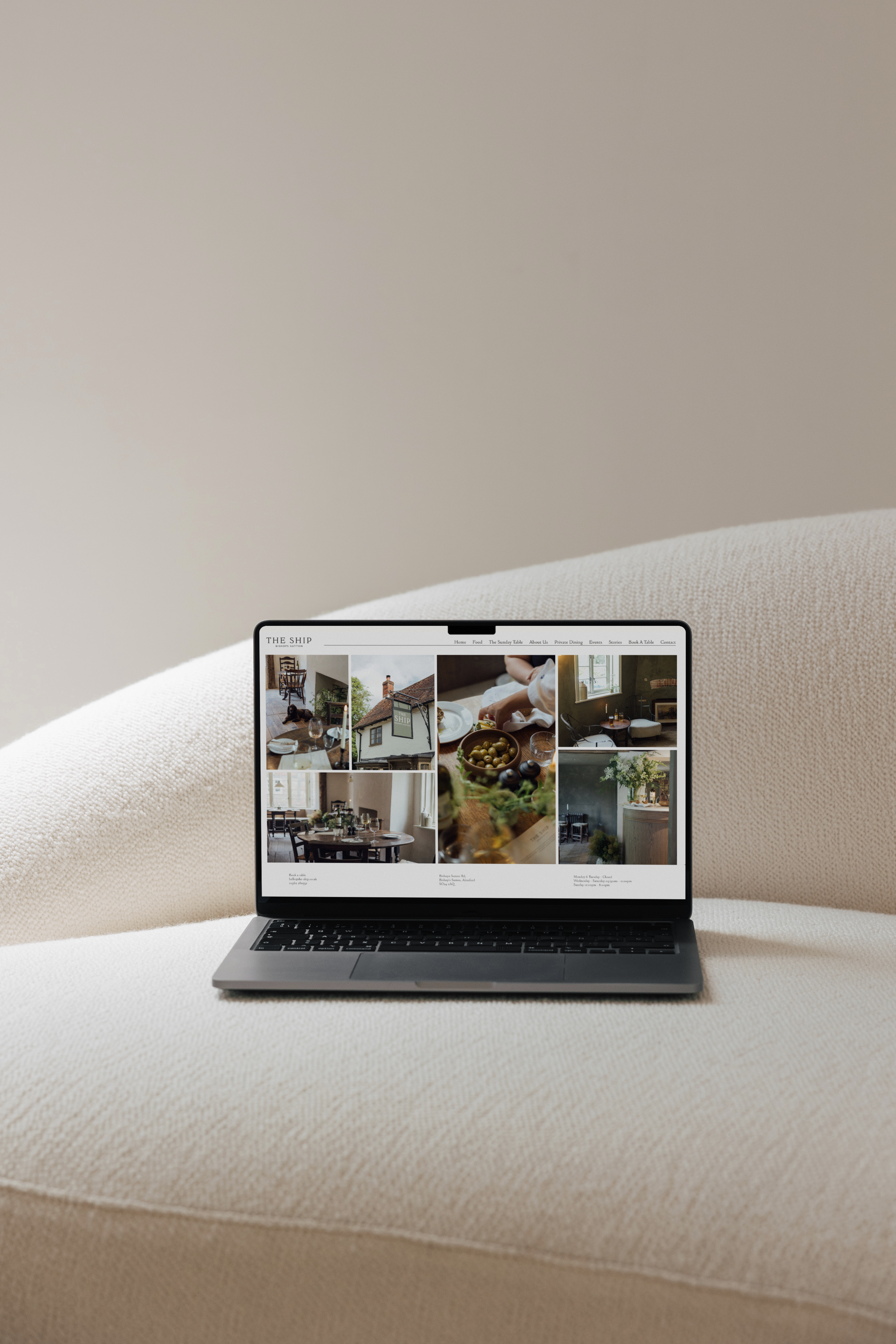 A laptop displaying a website with multiple photos of a cozy restaurant interior, food, and tables, placed on a white textured surface.