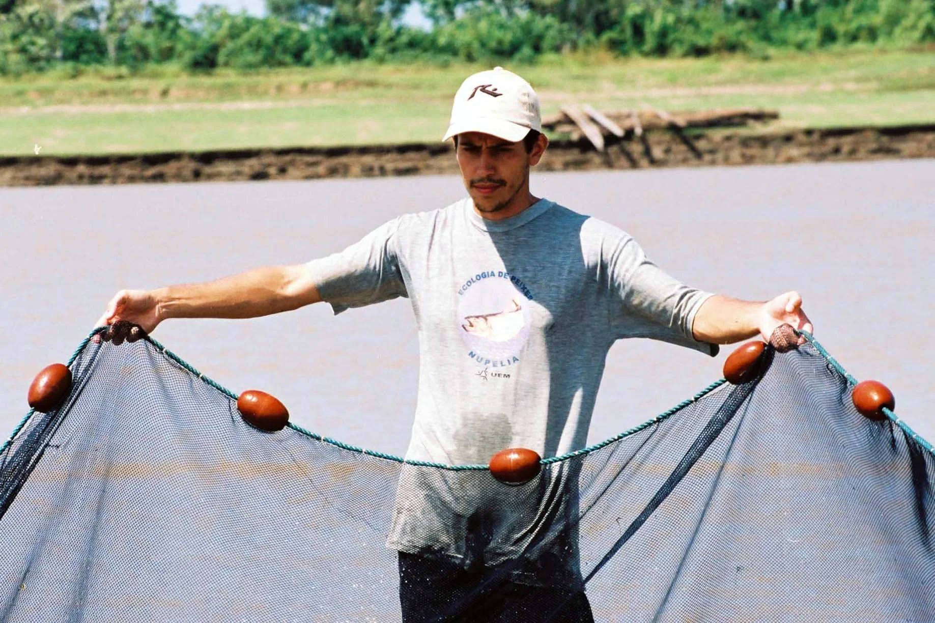 A man fishing in a body of water with a net.