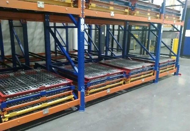 Industrial full support pushback storage rack with multiple levels of orange, blue, yellow, and red pushback racks.