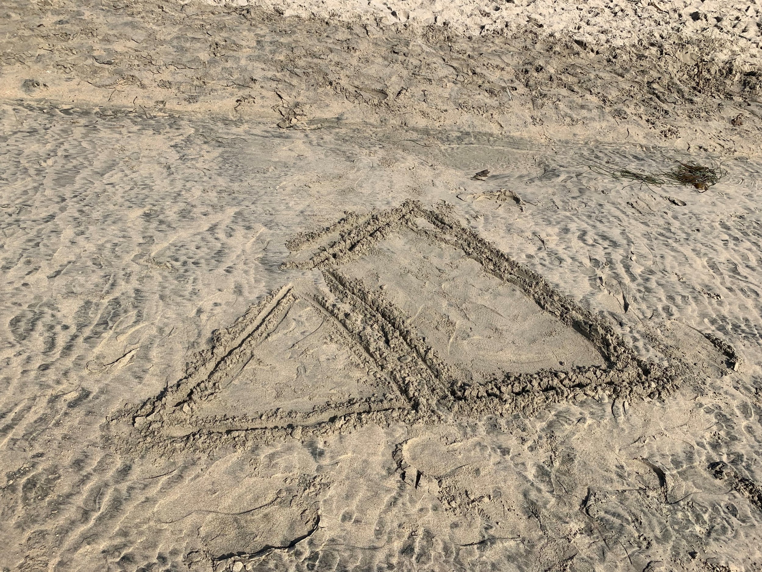 Advance logo carved into sand on a beach.