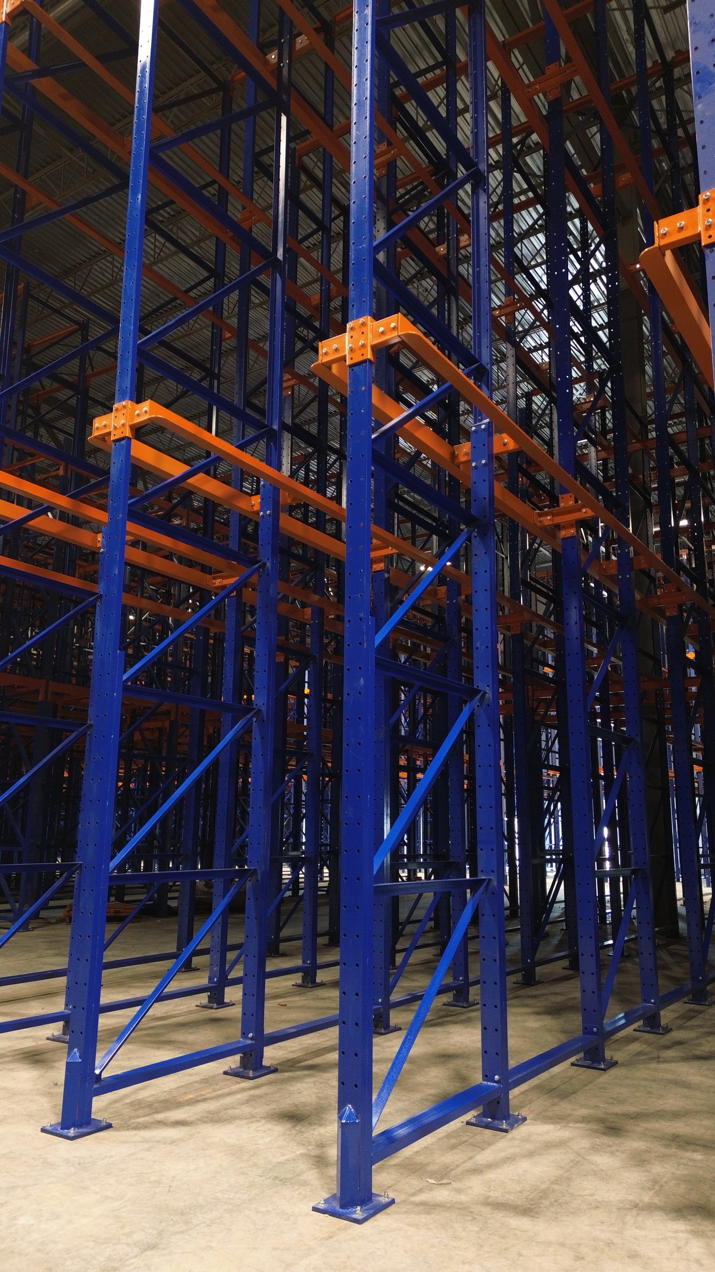 Empty warehouse shelving racks with blue and orange metal frames, built for storage.