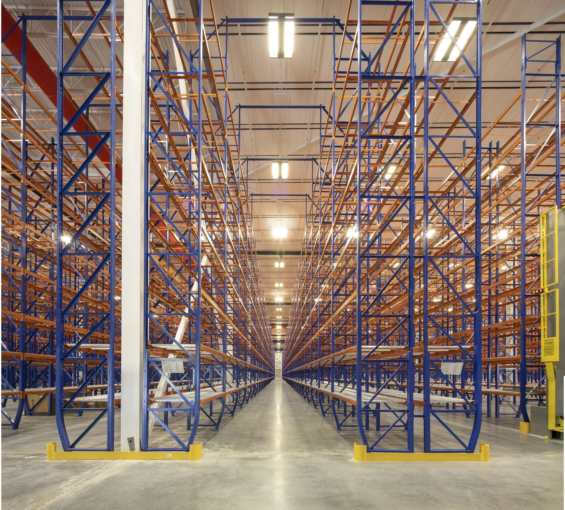 Multiple levels of warehouse shelving filled with boxes and a crane in the background.