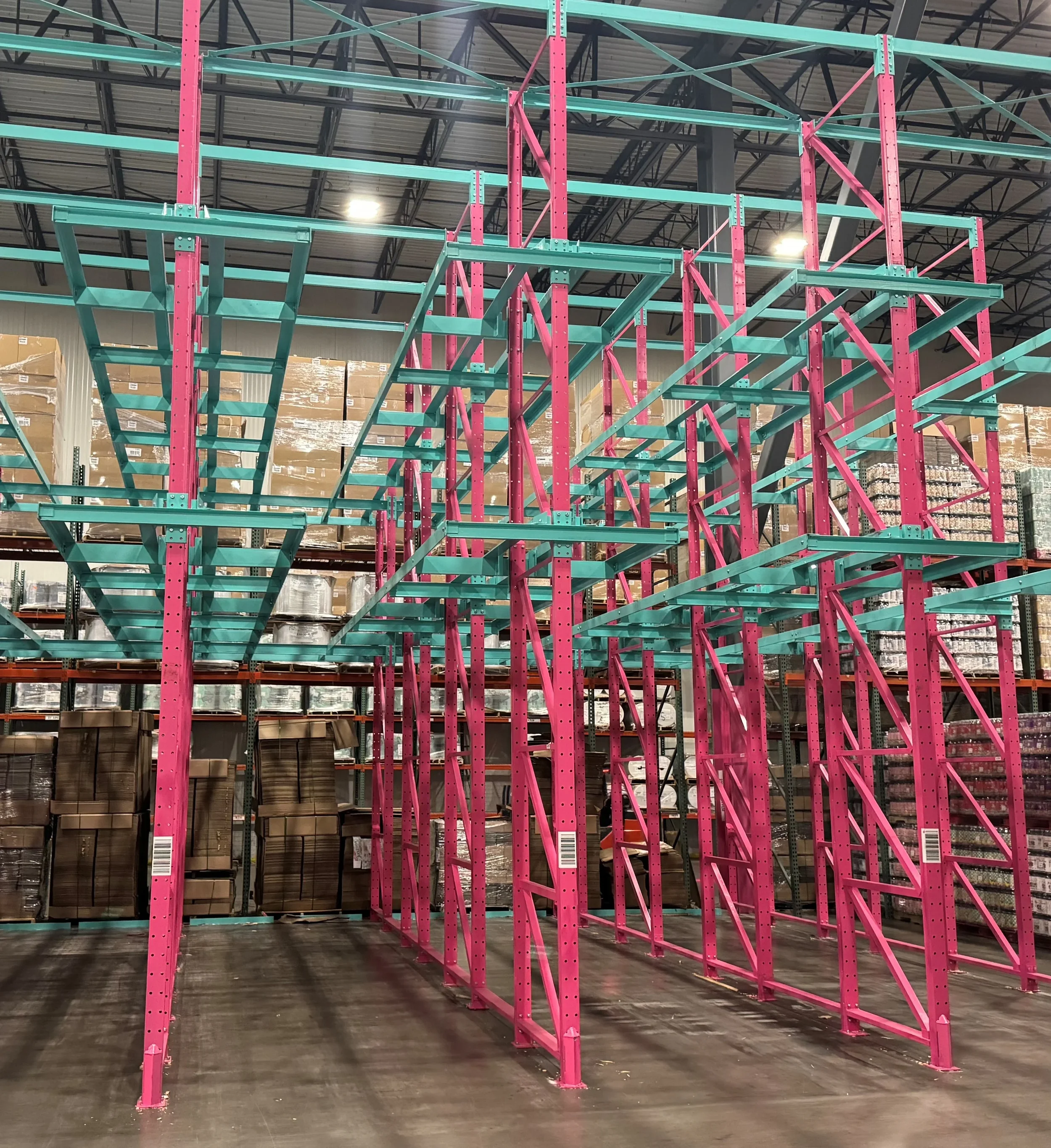 Empty warehouse with pink and turquoise two-wide racking.
