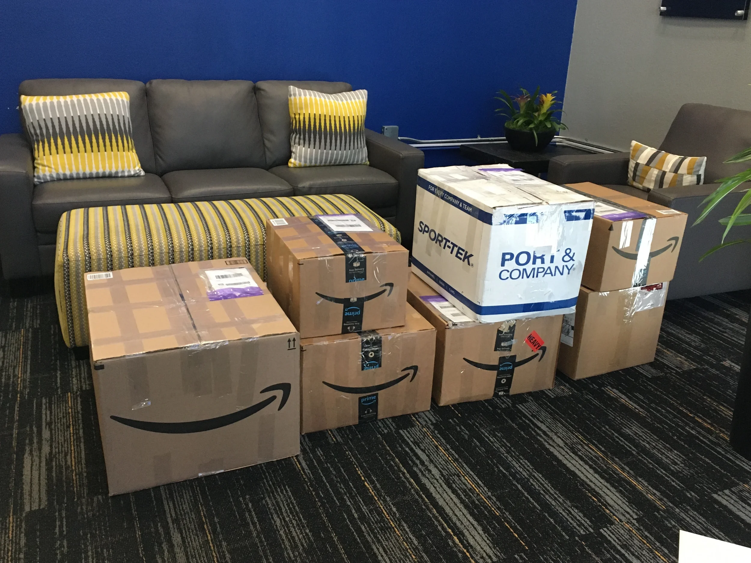Multiple cardboard boxes with Amazon Prime labels are in a waiting area.
