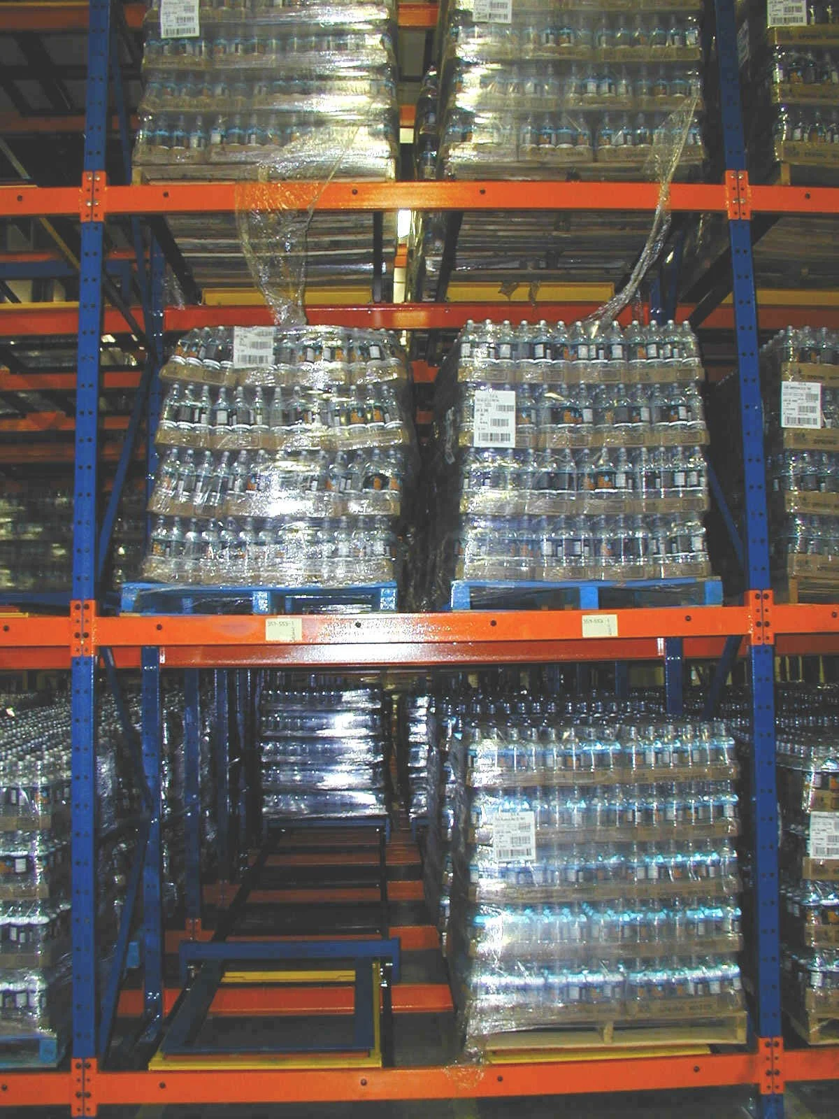 Large pallets of bottled water stacked on warehouse shelves.