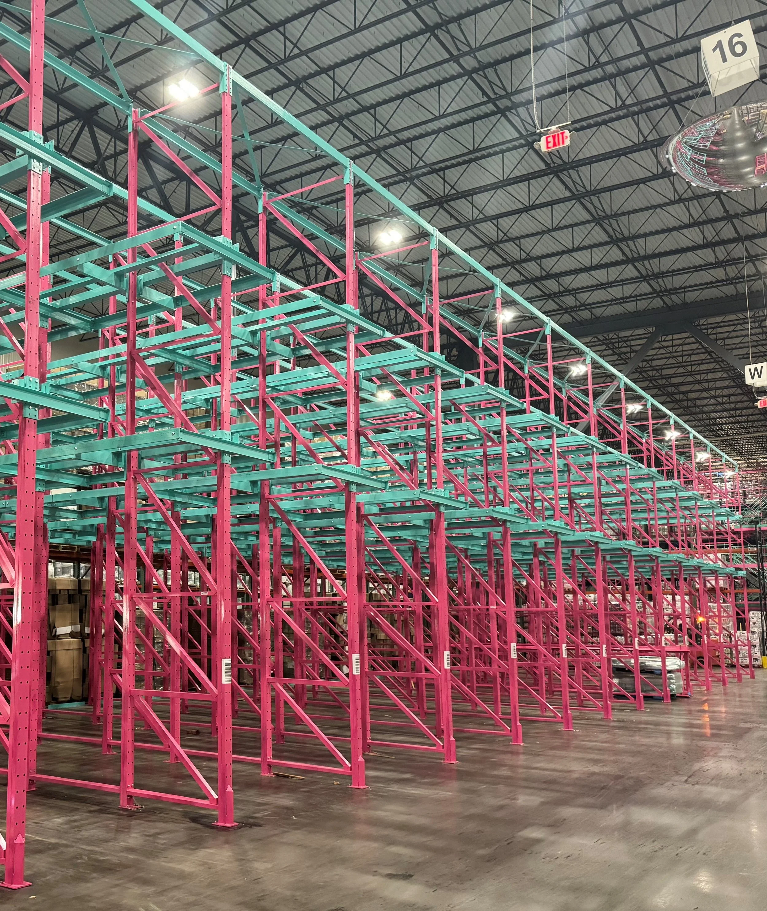 Empty warehouse with pink and teal two-wide racking.