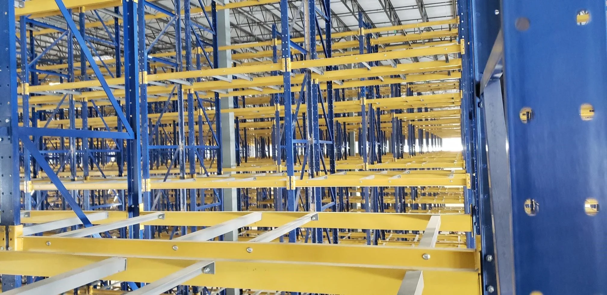 Inside a warehouse with blue and yellow selective pallet rack.
