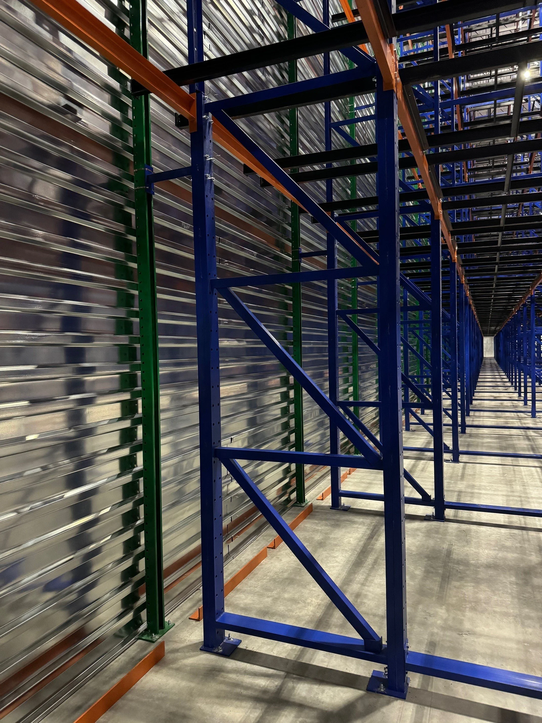 Empty industrial shelving units with metal and plastic beams in a warehouse.