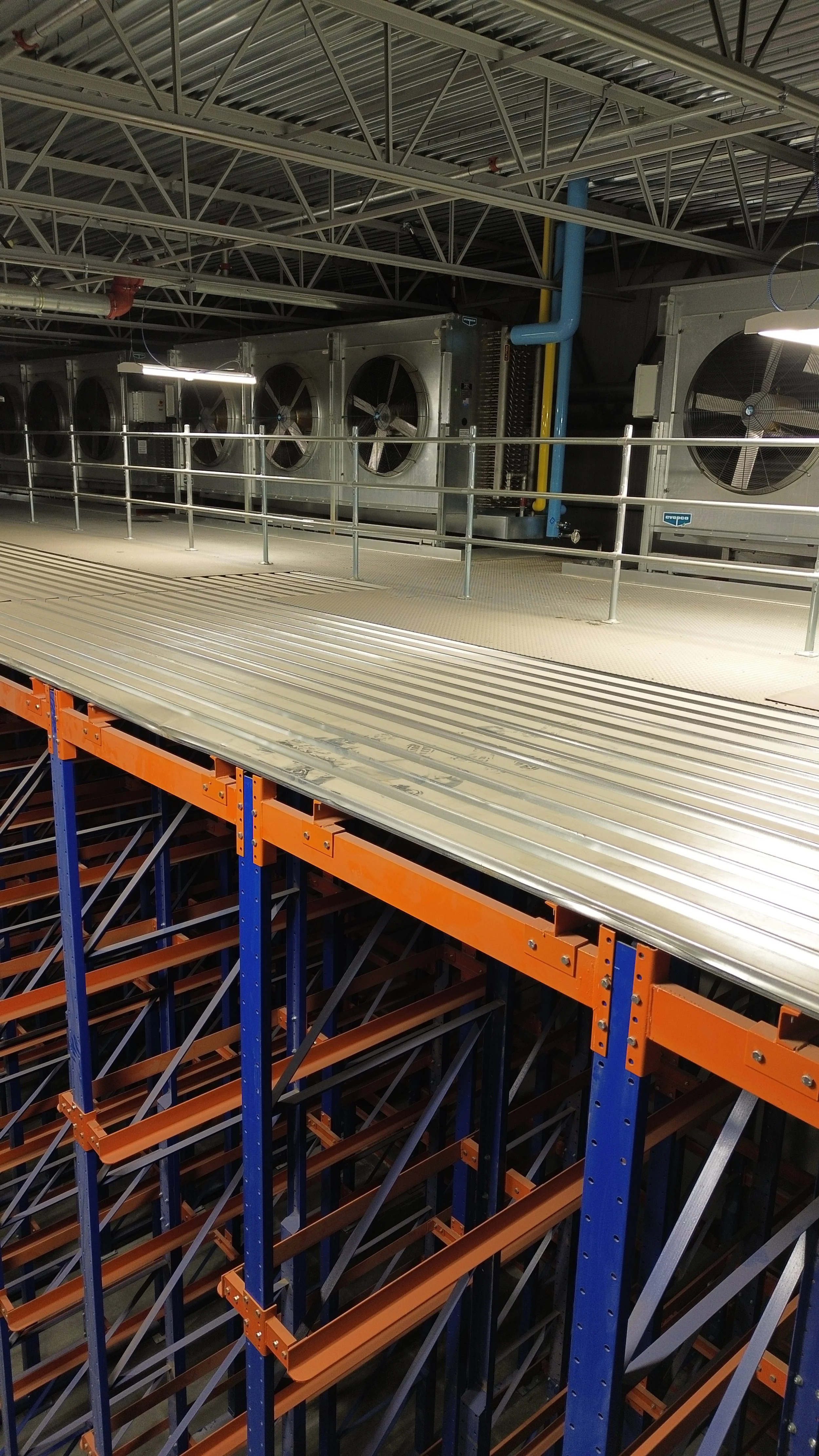 Industrial cooling system with large fans and pipes inside a warehouse or factory.