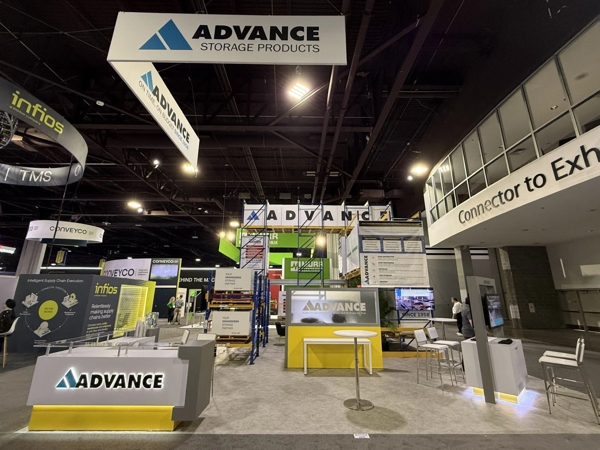 Trade show booth for Advance Storage Products, featuring signage, product displays, and seating area.