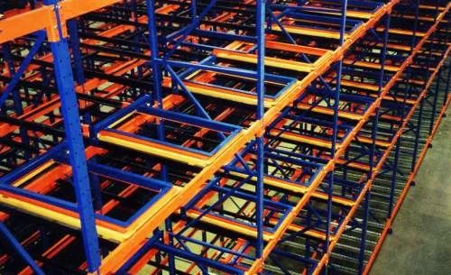 Warehouse pushback storage racks with orange and blue metal frames.