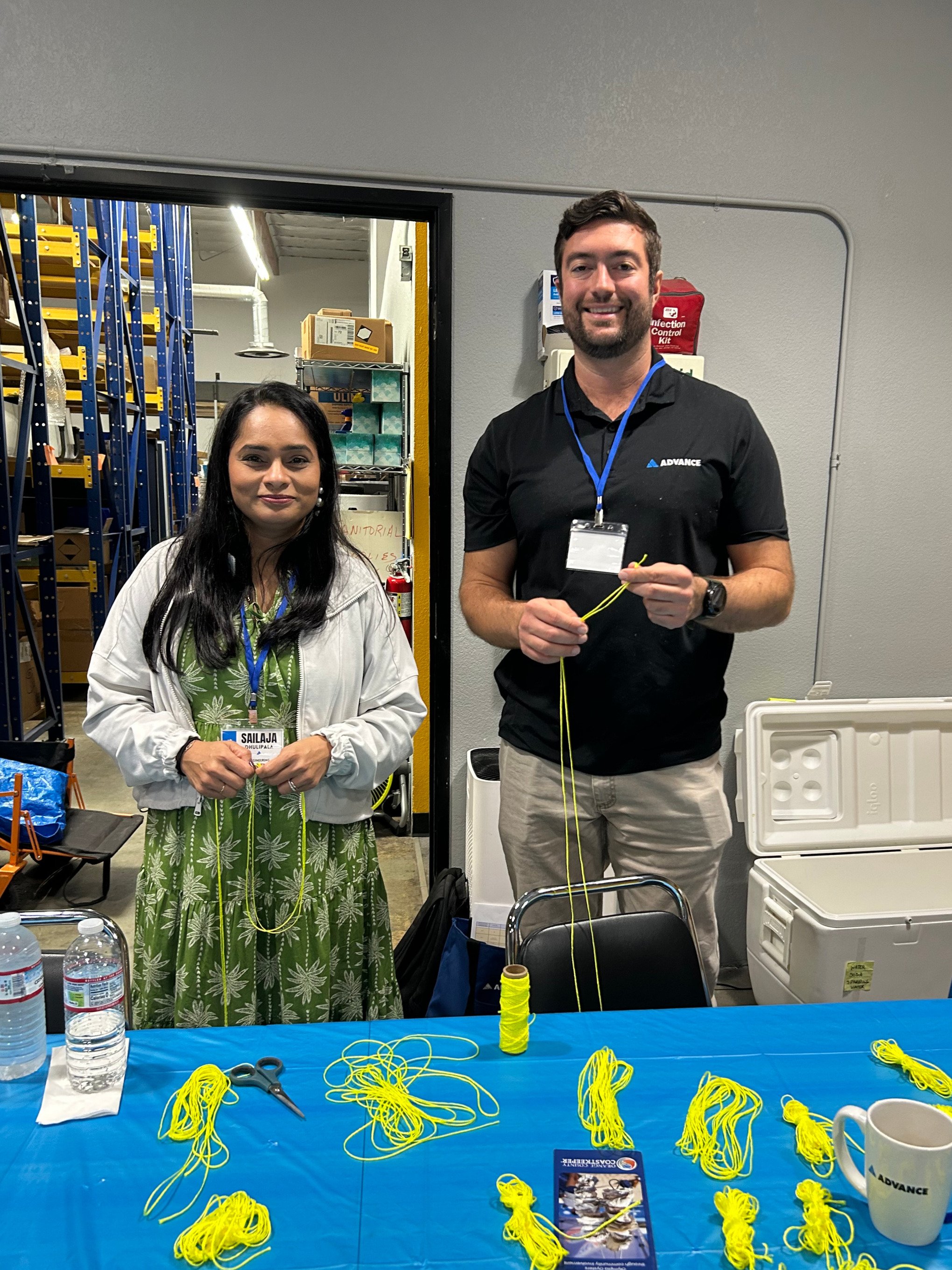 Two Advance employees smile in front of bunches of yellow twine they've organized.