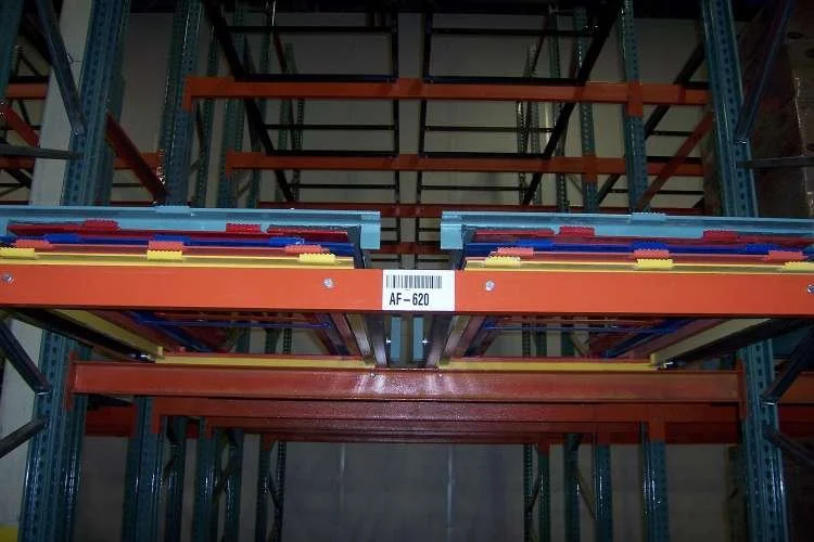 Industrial pushback warehouse shelving with colorful plastic bins on orange metal racks.