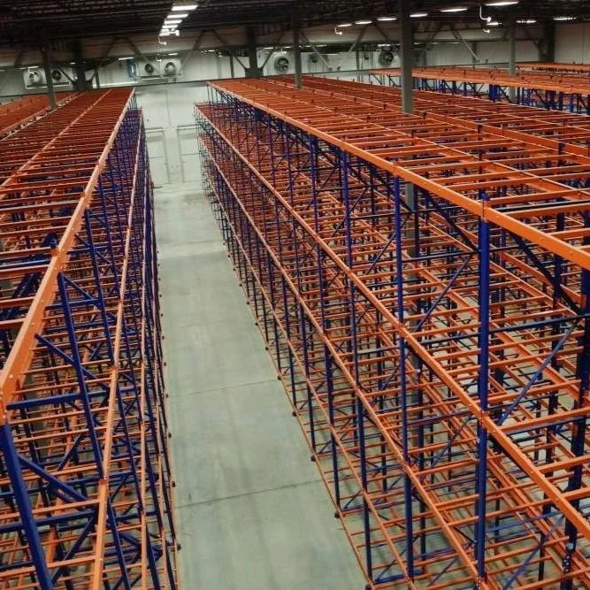 View of empty warehouse with tall, blue and orange pushback racking.