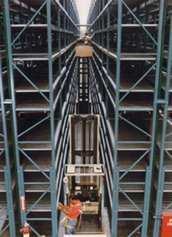 A person in a warehouse within a very narrow aisle racking system.