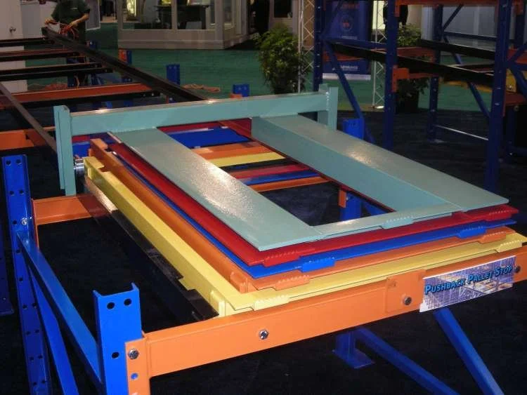 Colorful pushback pallet rack system with multiple pallets stacked on orange and blue metal frames.