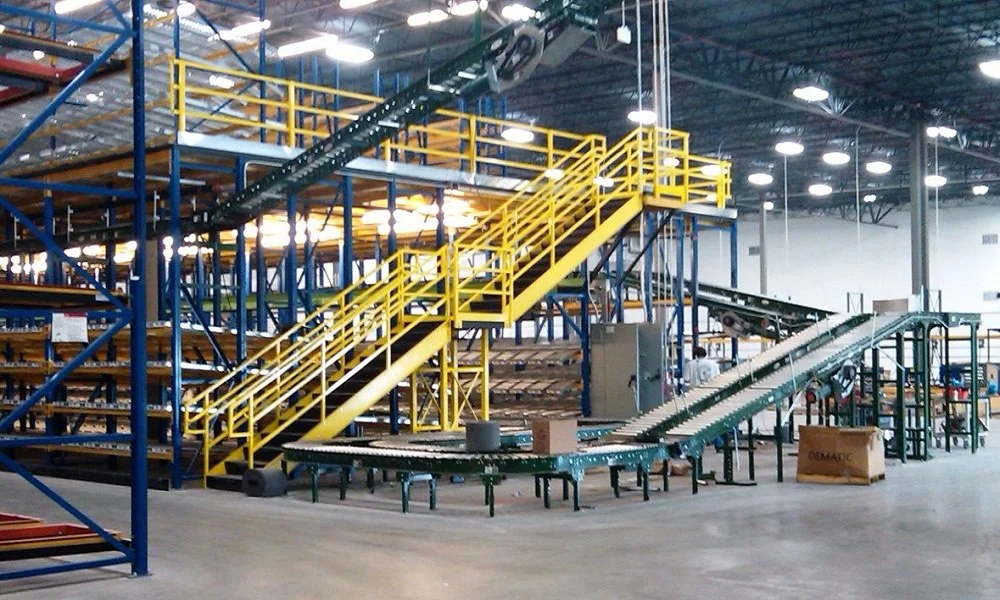 Industrial warehouse with a pick module, storage racks, and yellow stairs.