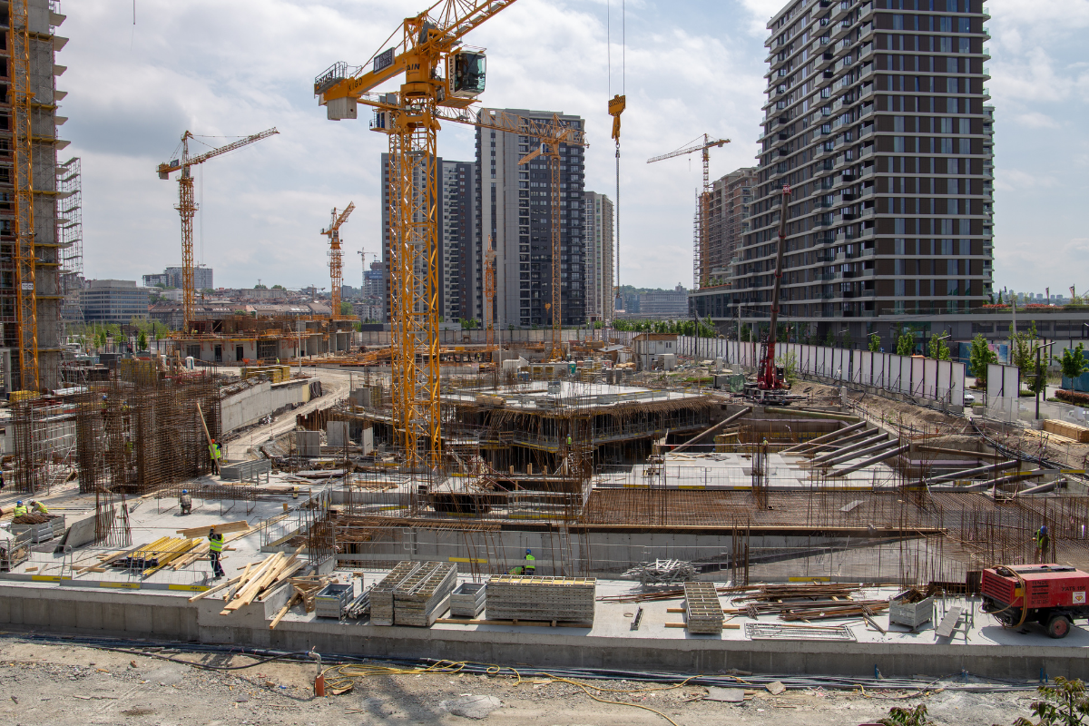Construction site with multiple cranes and buildings under construction in an urban area.
