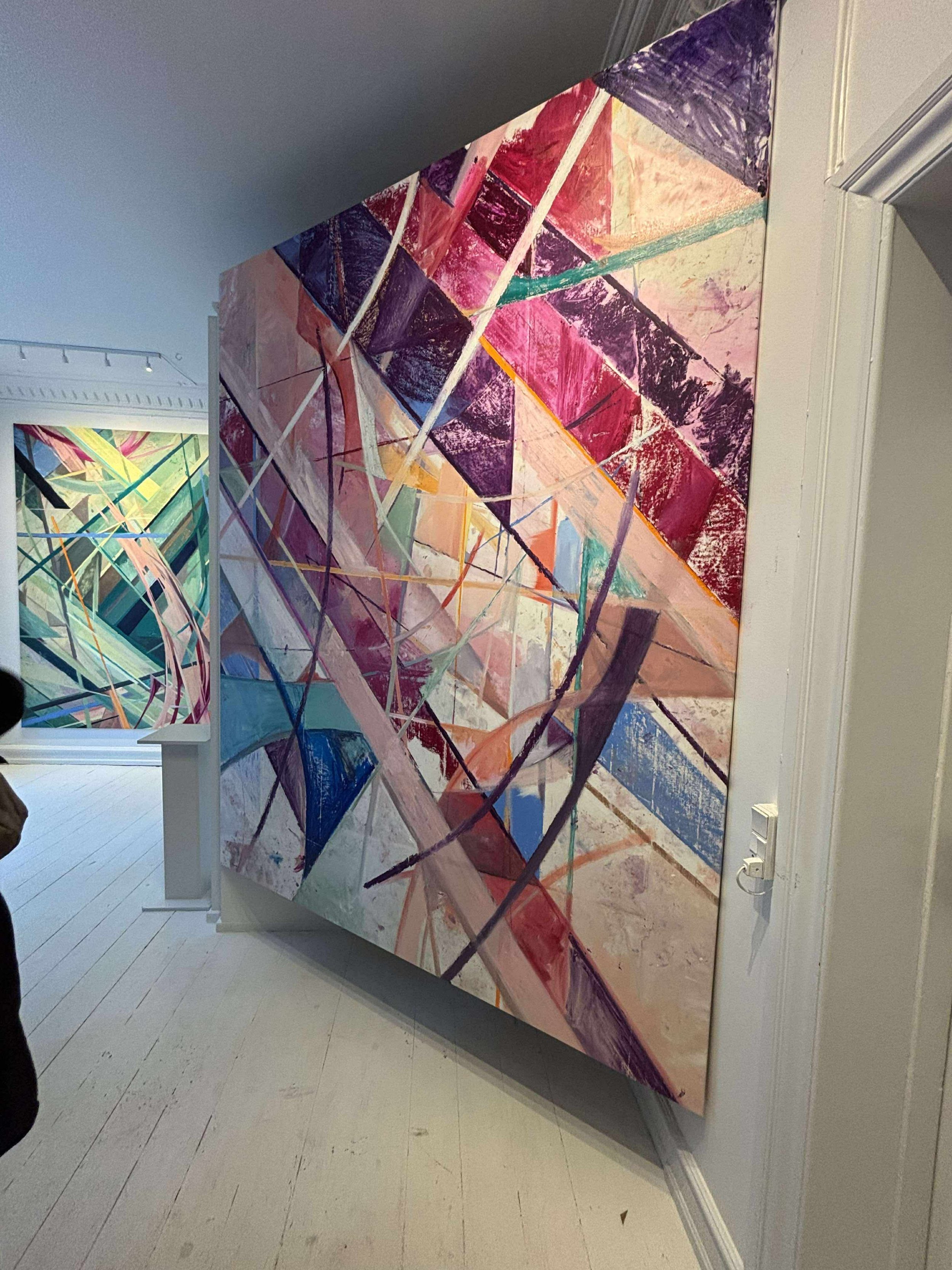 Colorful abstract geometric painting displayed on a wall in an art gallery.