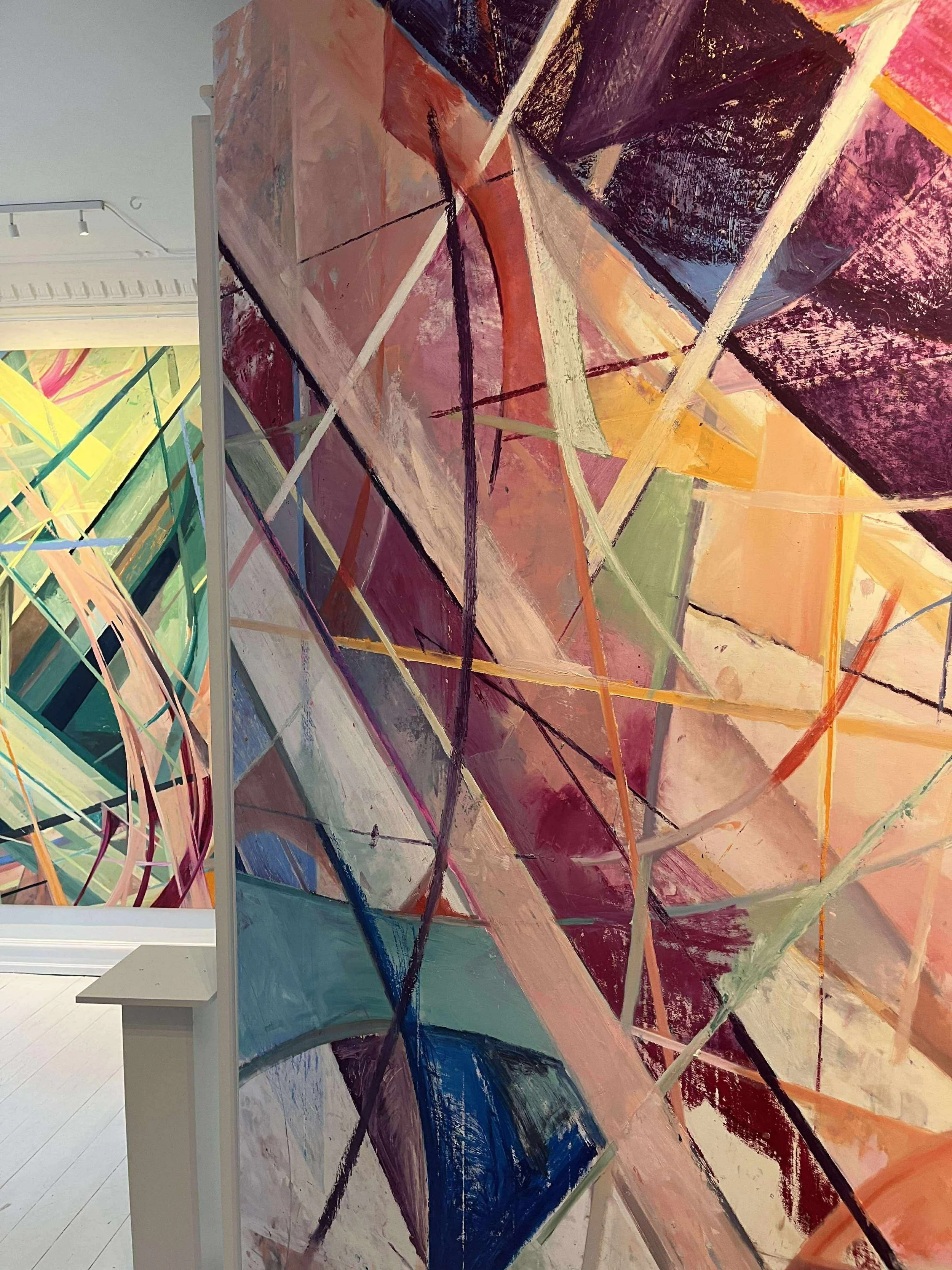 Abstract colorful geometric painting with intersecting lines and shapes in shades of pink, purple, green, and blue.