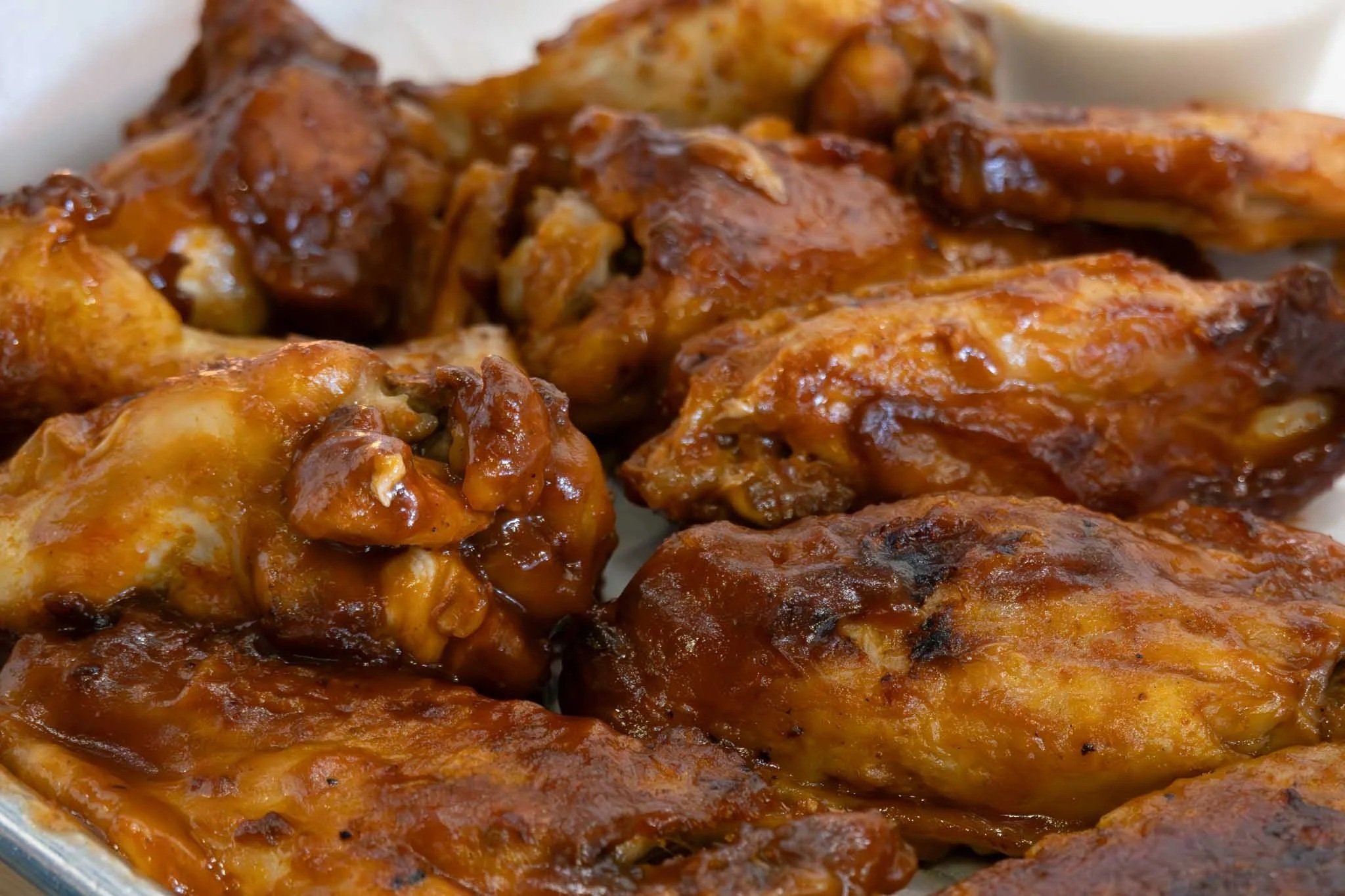 Close-up of cooked chicken wings covered in barbecue sauce.