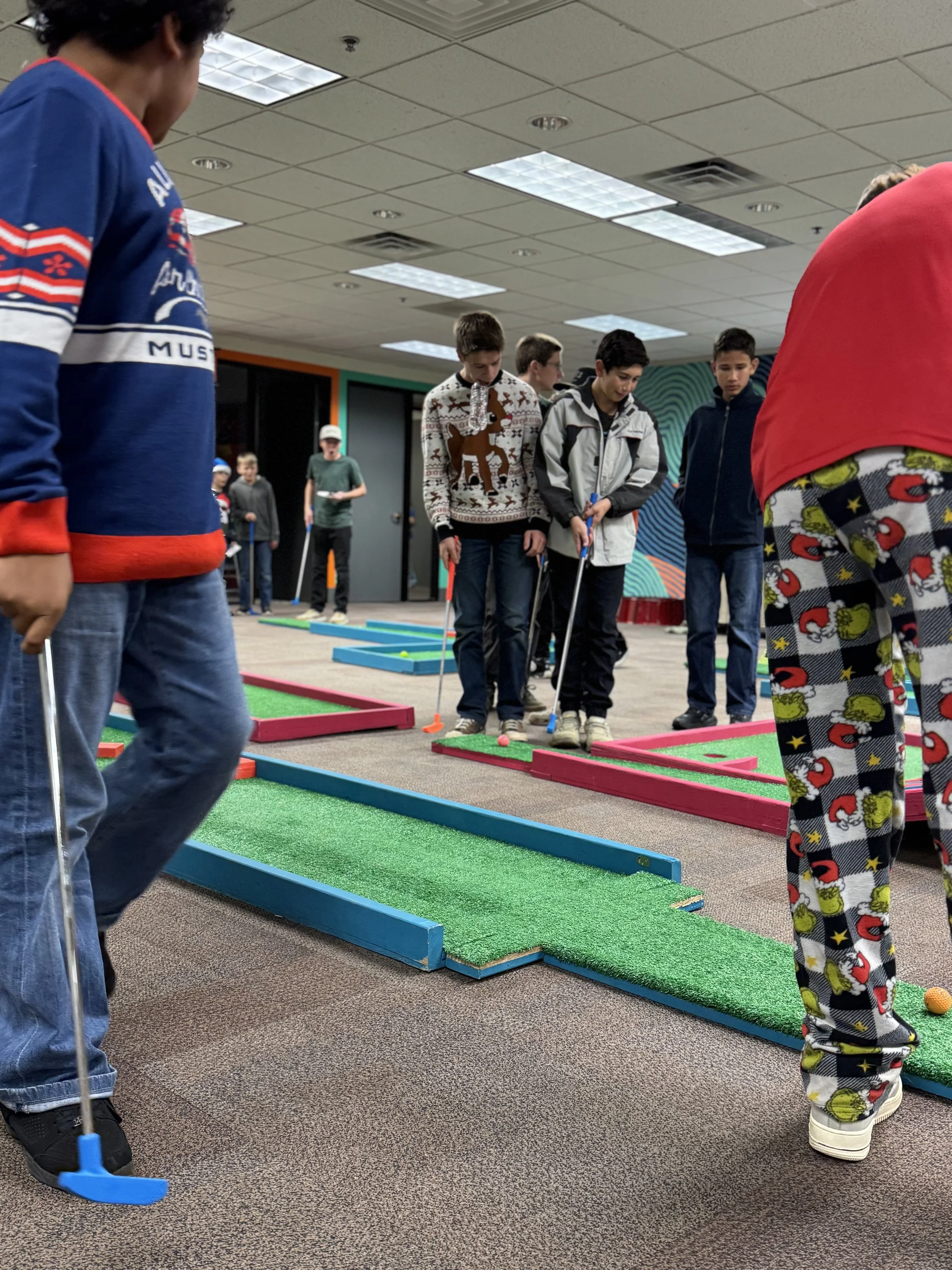 Kids playing mini golf indoors, focusing on their shots on colorful mini golf courses with artificial turf.