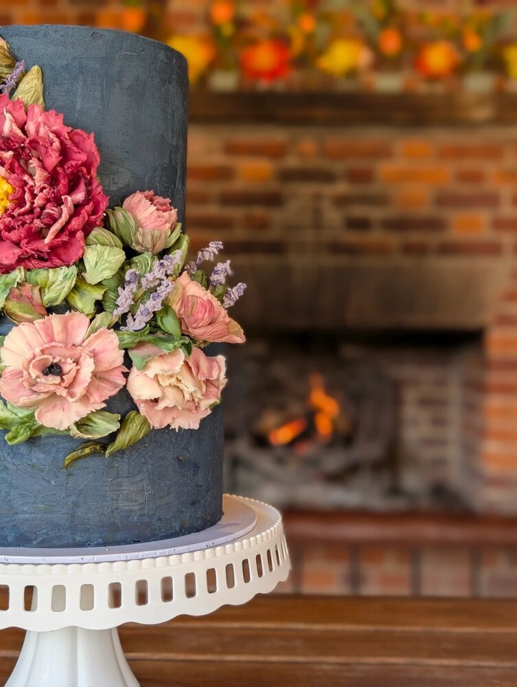 Close-up of a luxury blue two-tiered wedding cake decorated in luxury Belgian white chocolate flowers. 