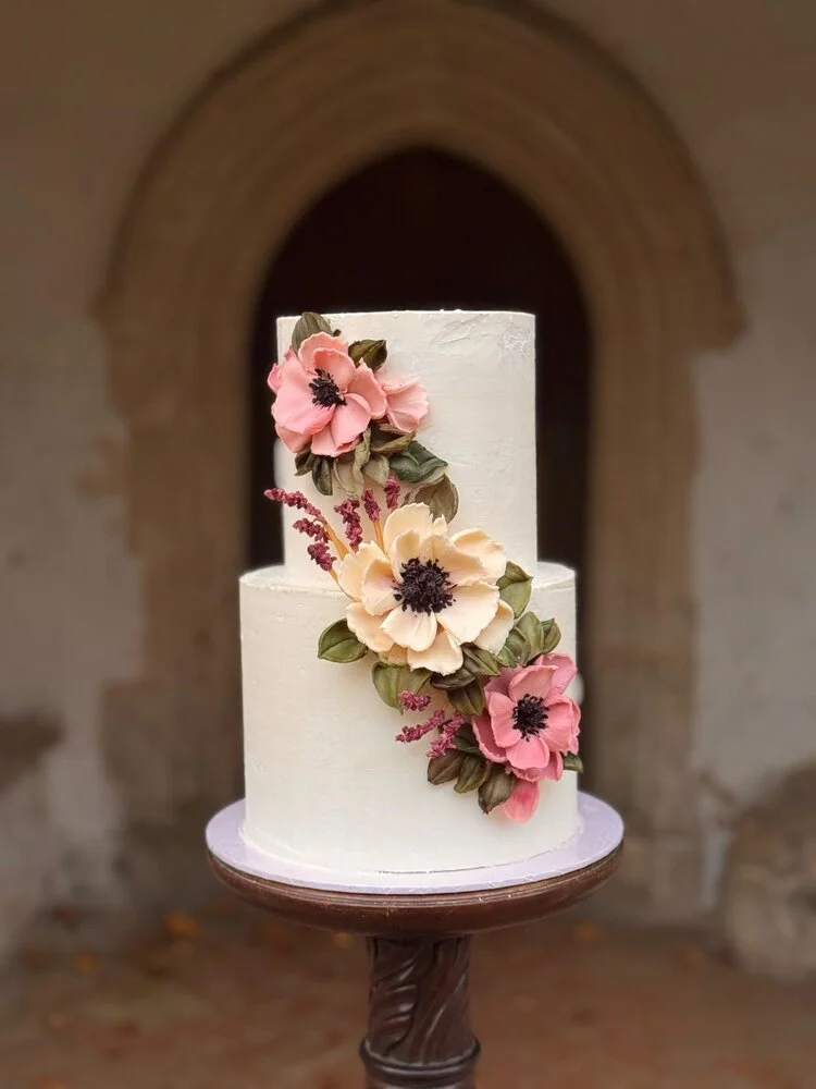 A two-tiered white wedding cake decorated with luxury hand-sculpted Belgian white chocolate.