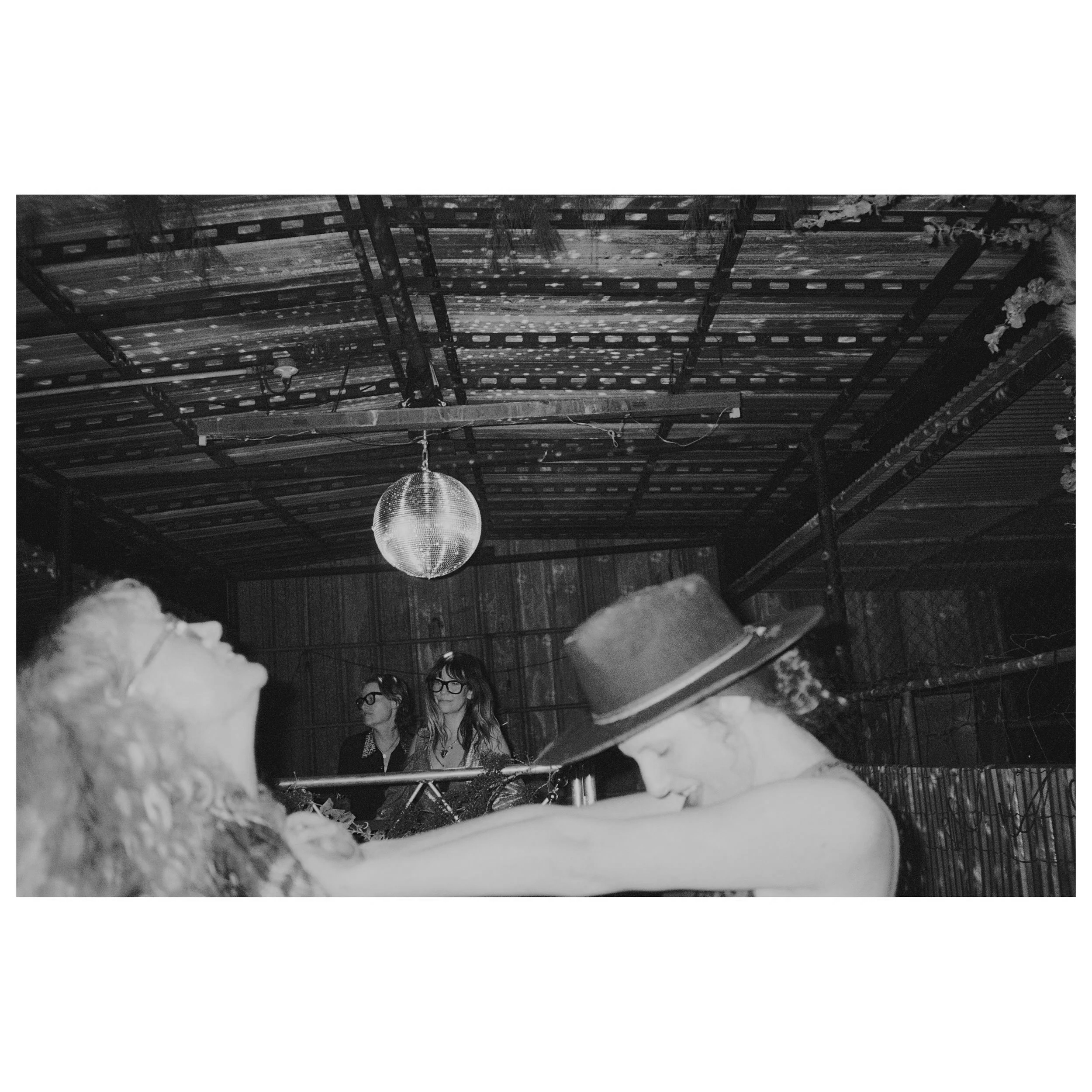 People dancing at a party with a disco ball overhead.