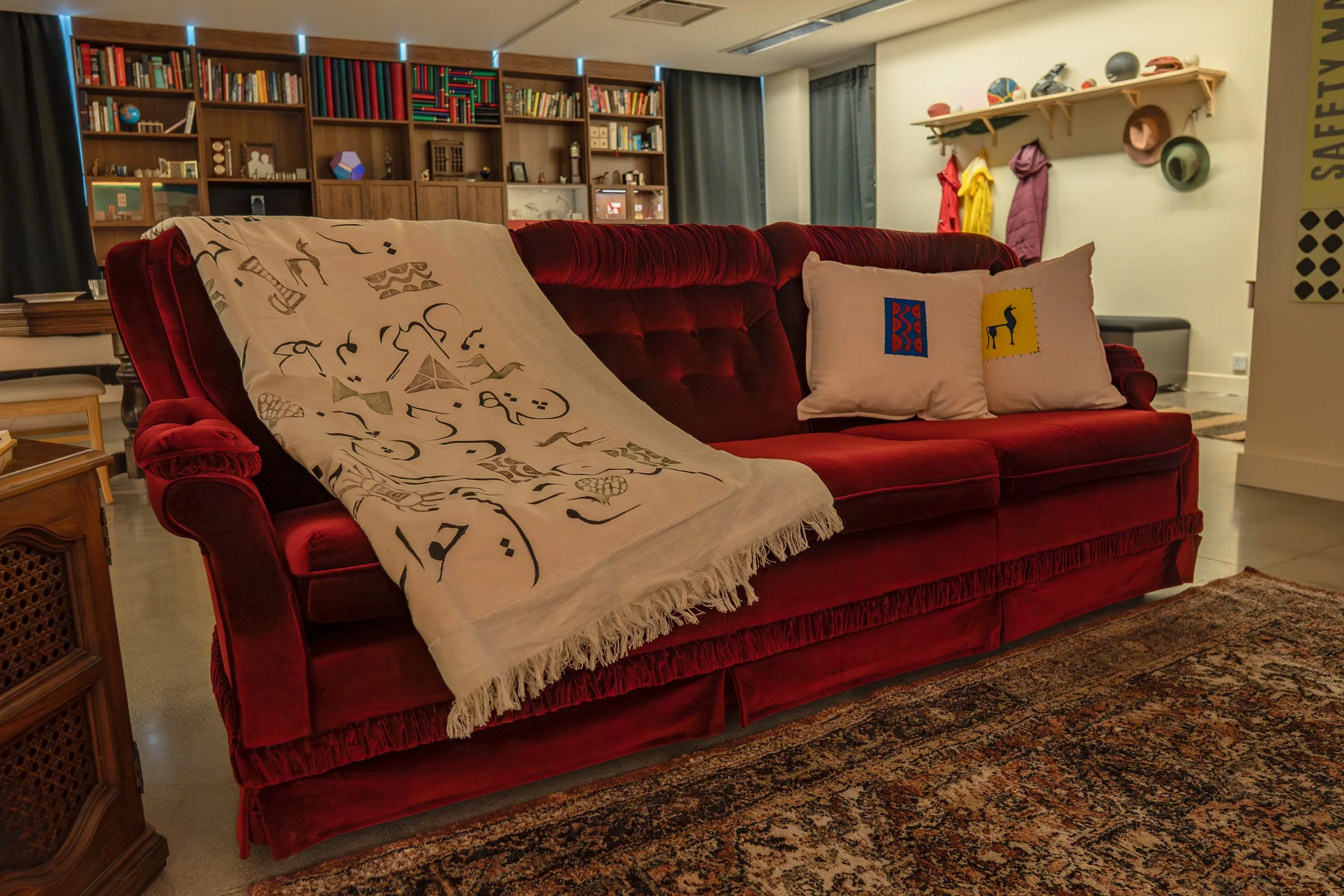 A red velvet couch with a hand printed throw and hand printed pillows