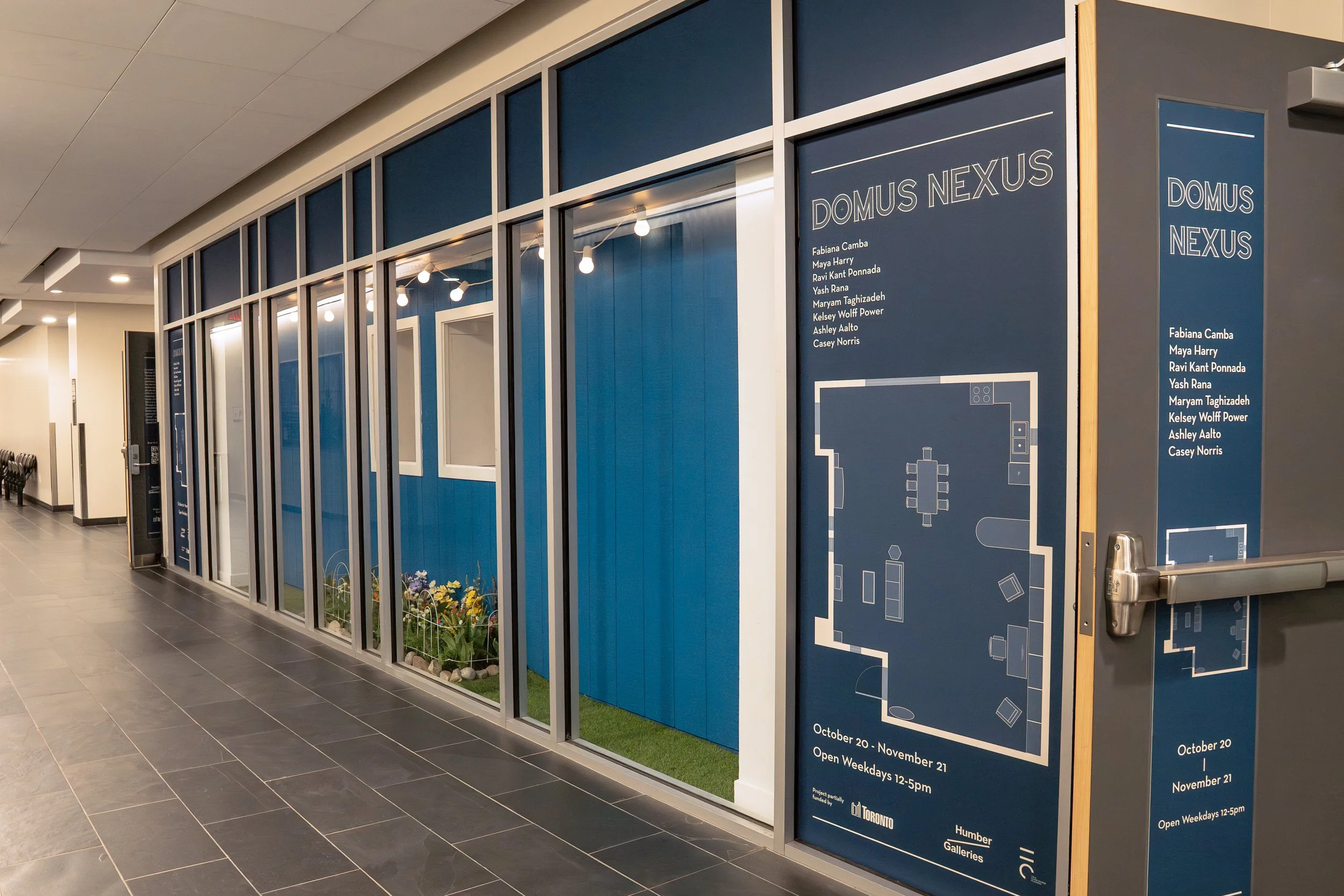 The outside of a blue house with flowers under the windows, built inside the L Space Gallery