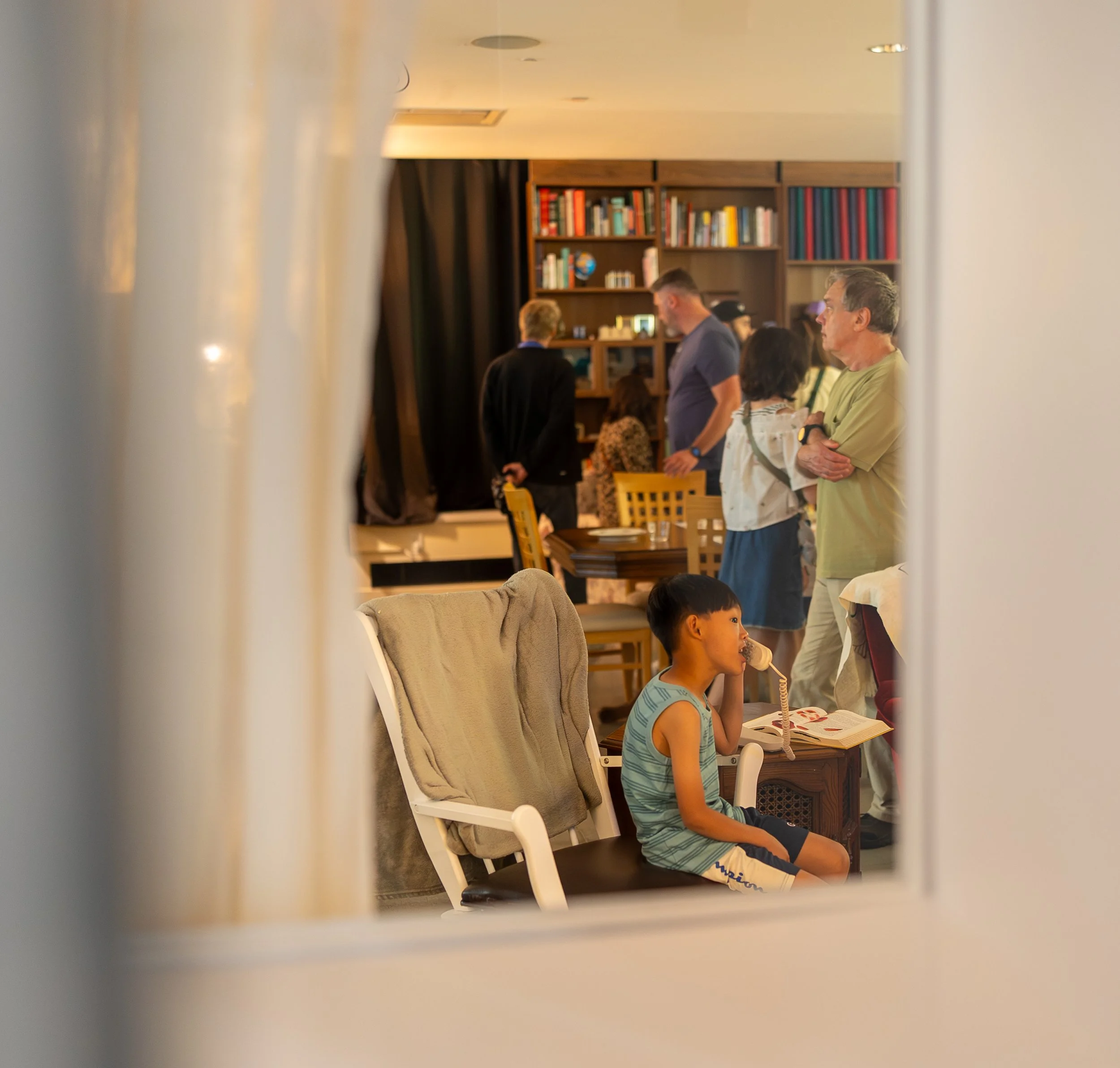 A window frames a boy sitting in the living room
