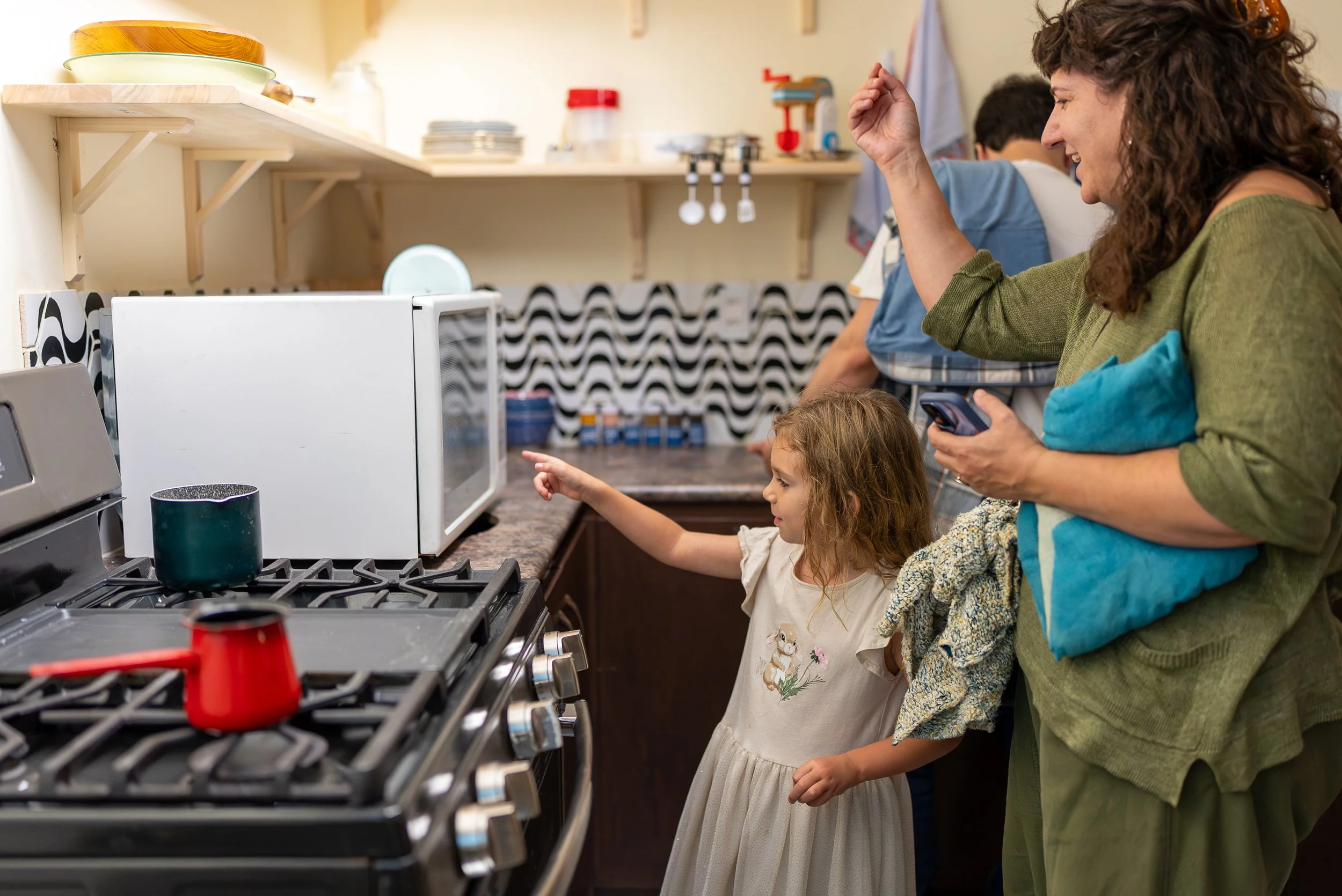 A woman and girl looking at the microwave in the kitchen