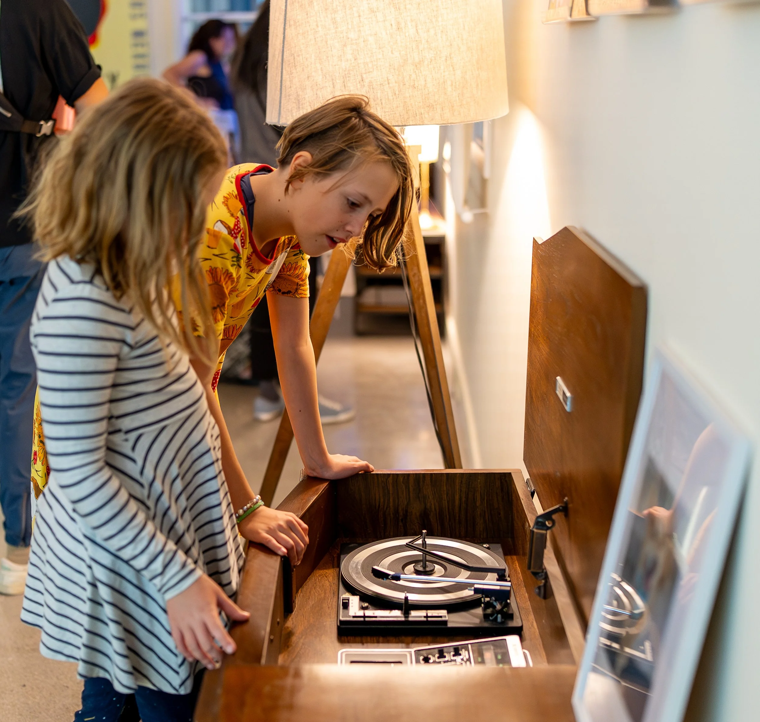 Two young people looking at the vintage record player/radio