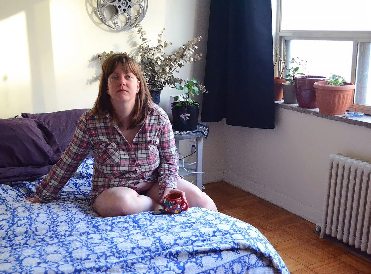 Lucy Dee sitting on her bed and drinking coffee