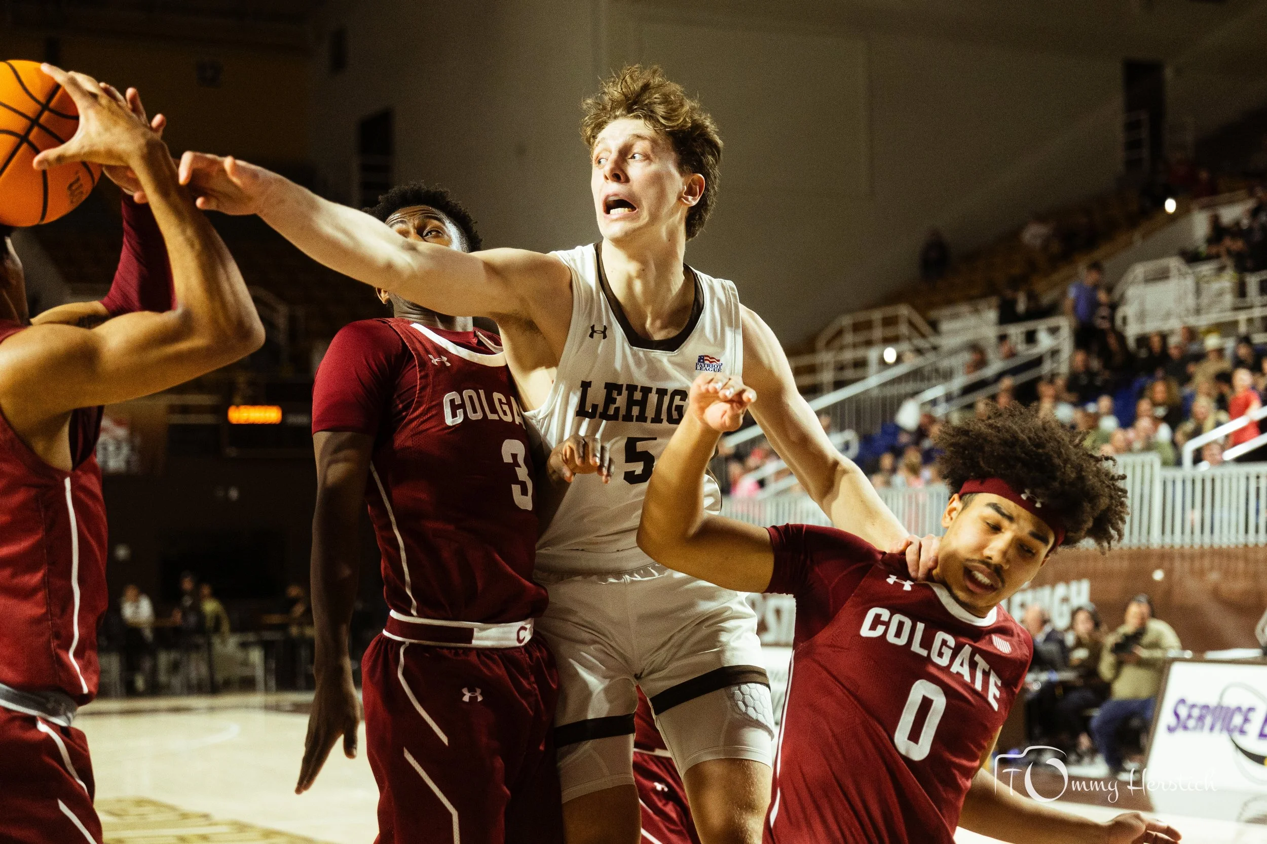 A basketball game with players from Lehigh and Colgate teams fighting for the ball.