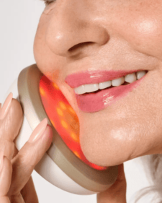 Close-up of a woman smiling while talking on a phone with a red and orange glow near her cheek.