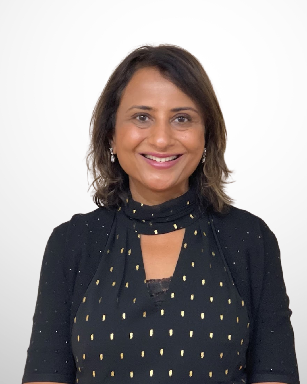 A smiling male doctor in a blue suit, wearing a shirt and tie, against a plain white background.