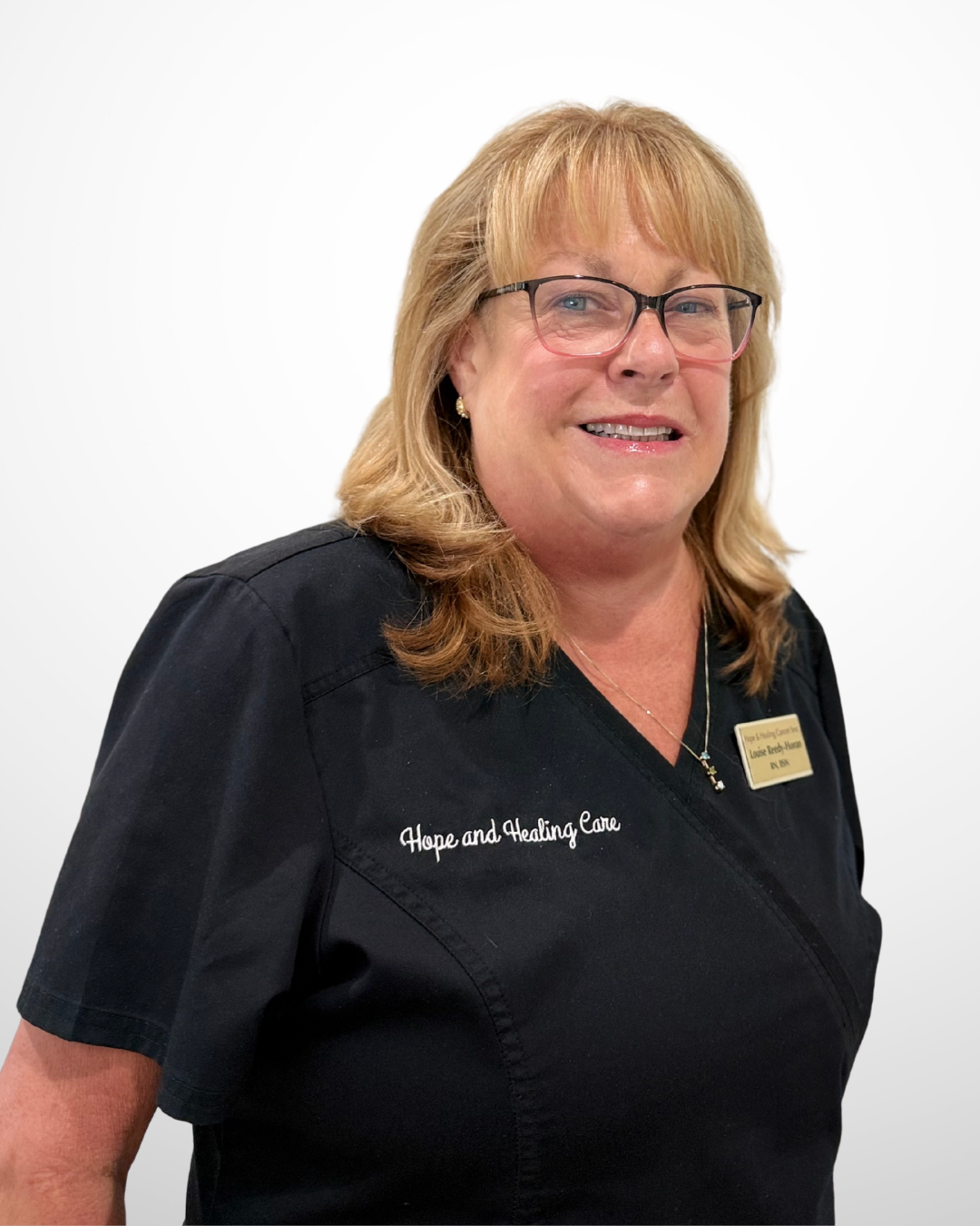 A smiling woman with blonde hair, glasses, and a black uniform with 'Hope and Healing Care' embroidered on it, against a plain white background.