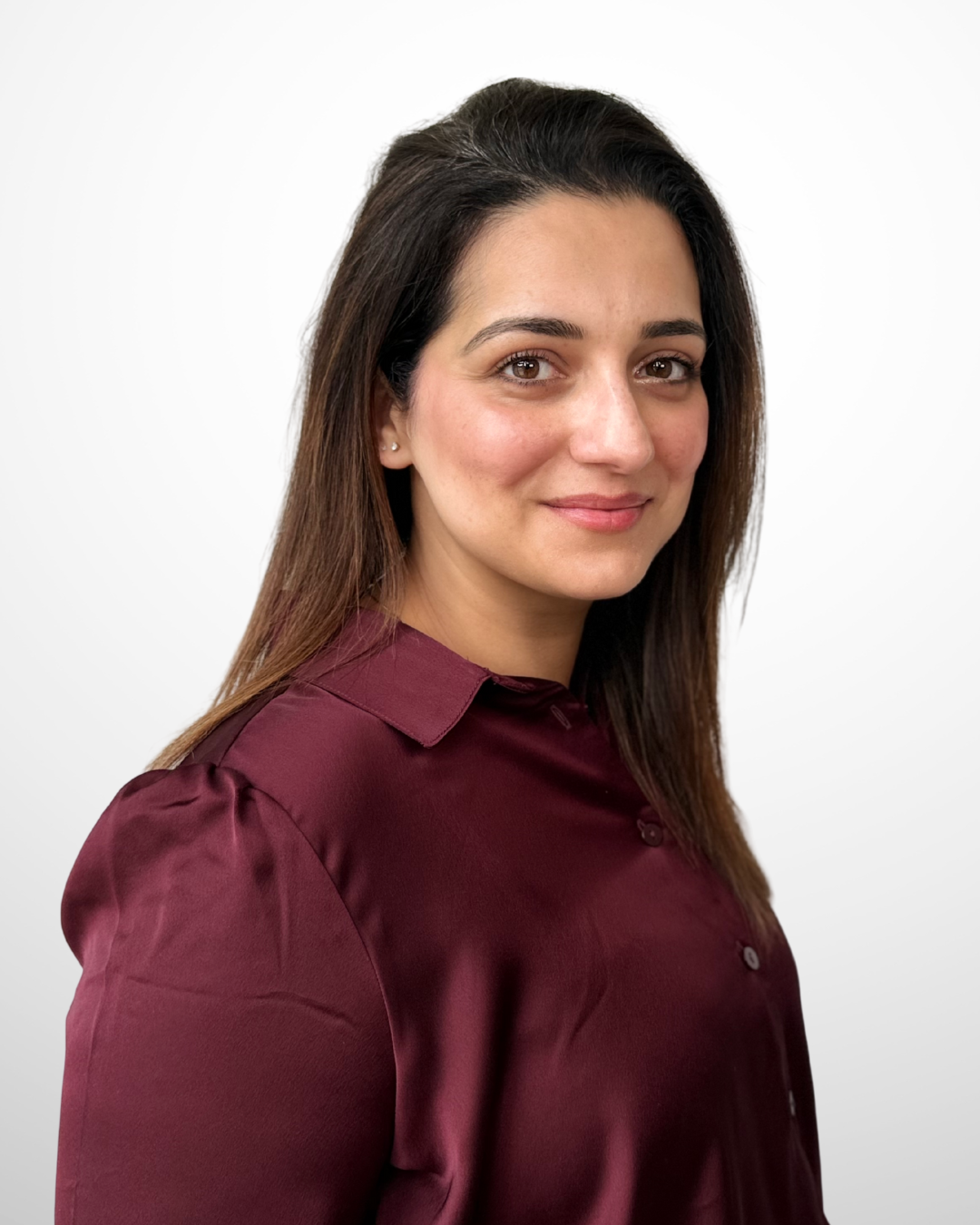 Portrait of a young woman with brown hair, smiling, wearing a maroon shirt, against a plain white background.