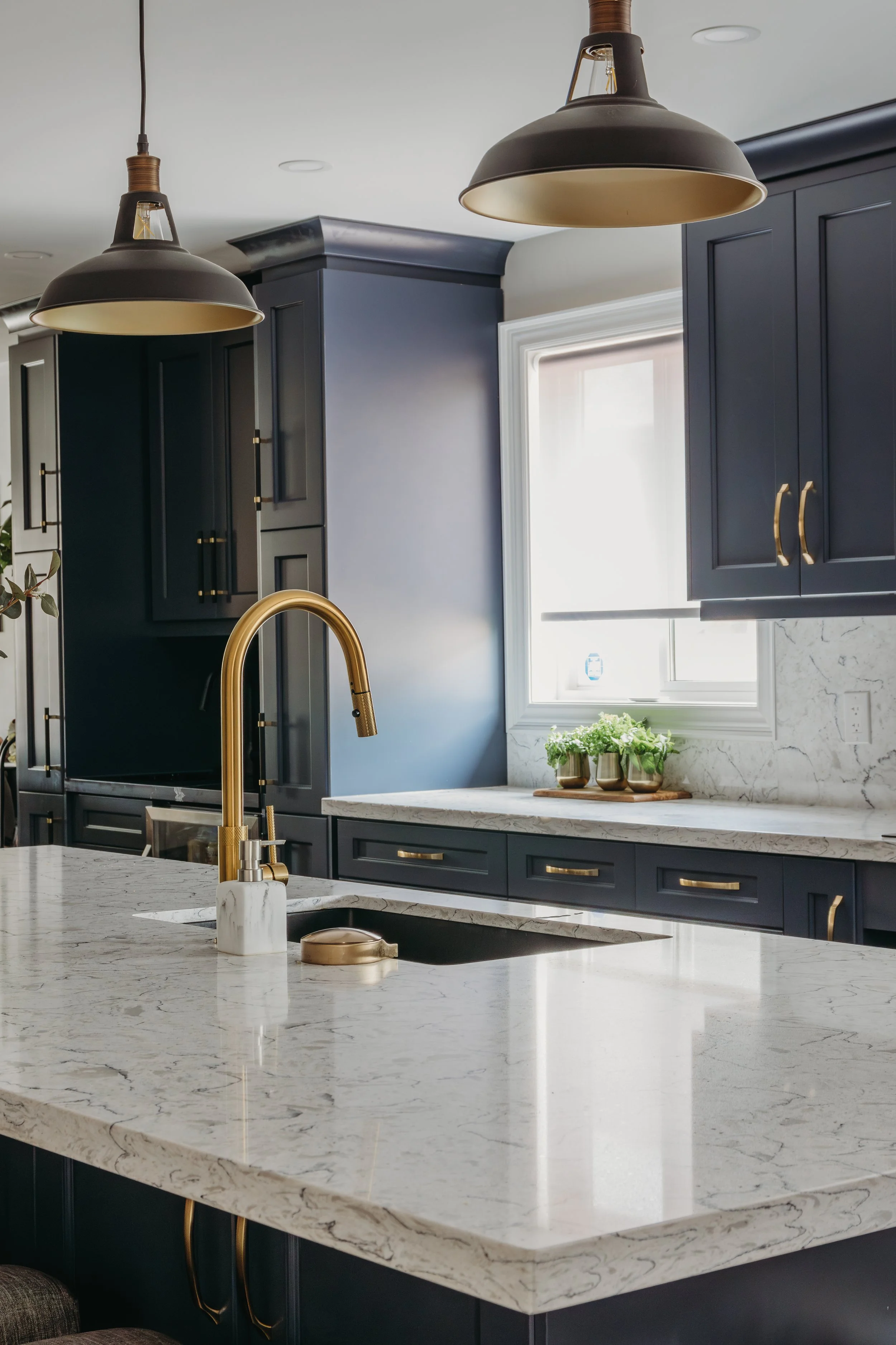White and navy blue quartz, gold faucet, cup washer at sink